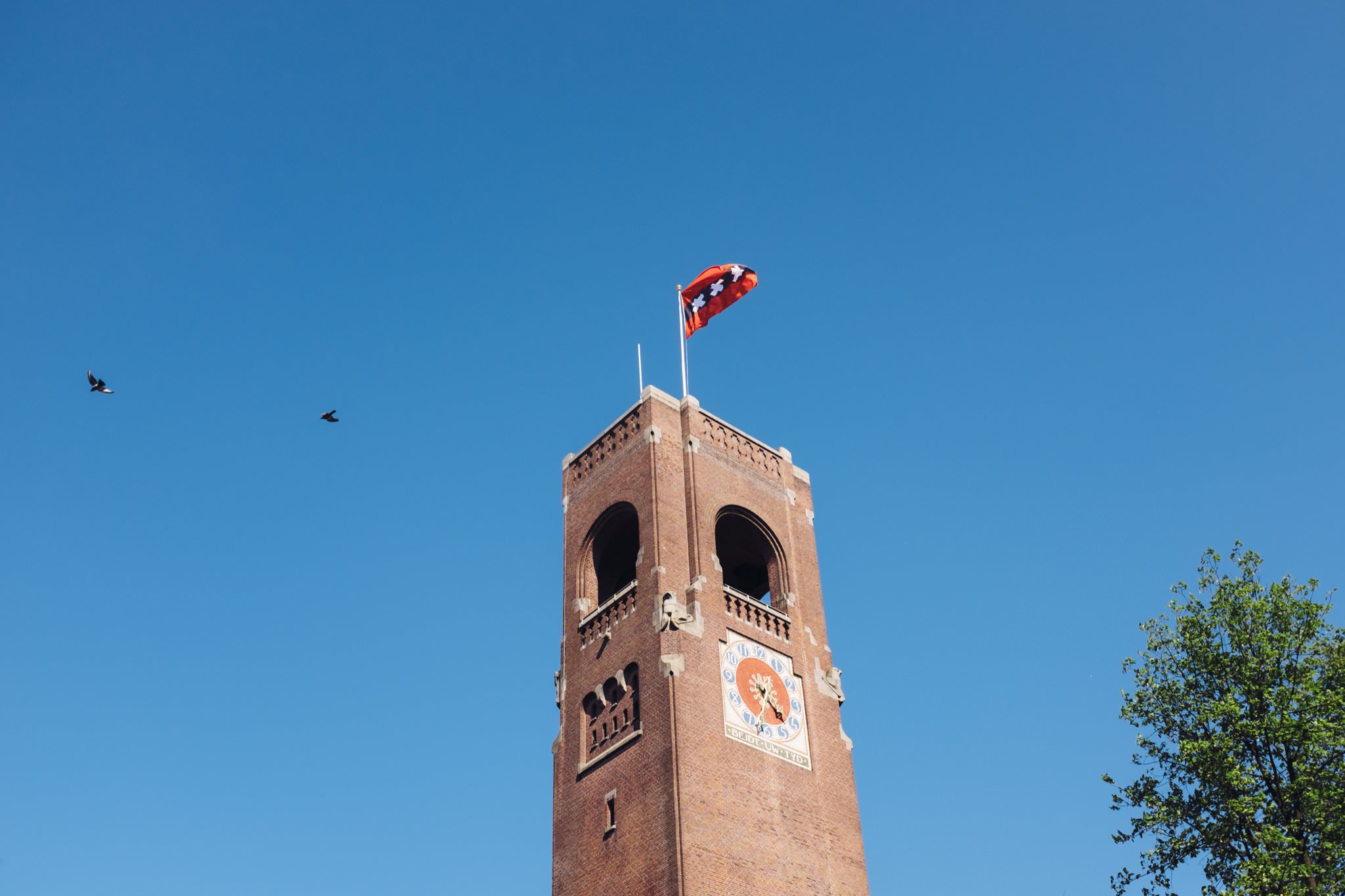 Amsterdam clock tower with orange flag.