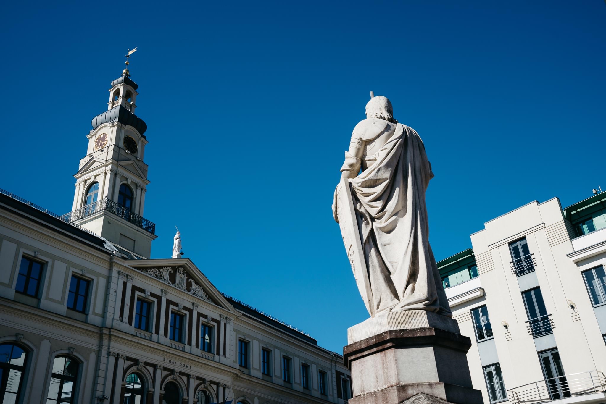 Rear view of a statue in Riga, Latvia, with the Riga Dome in the background.