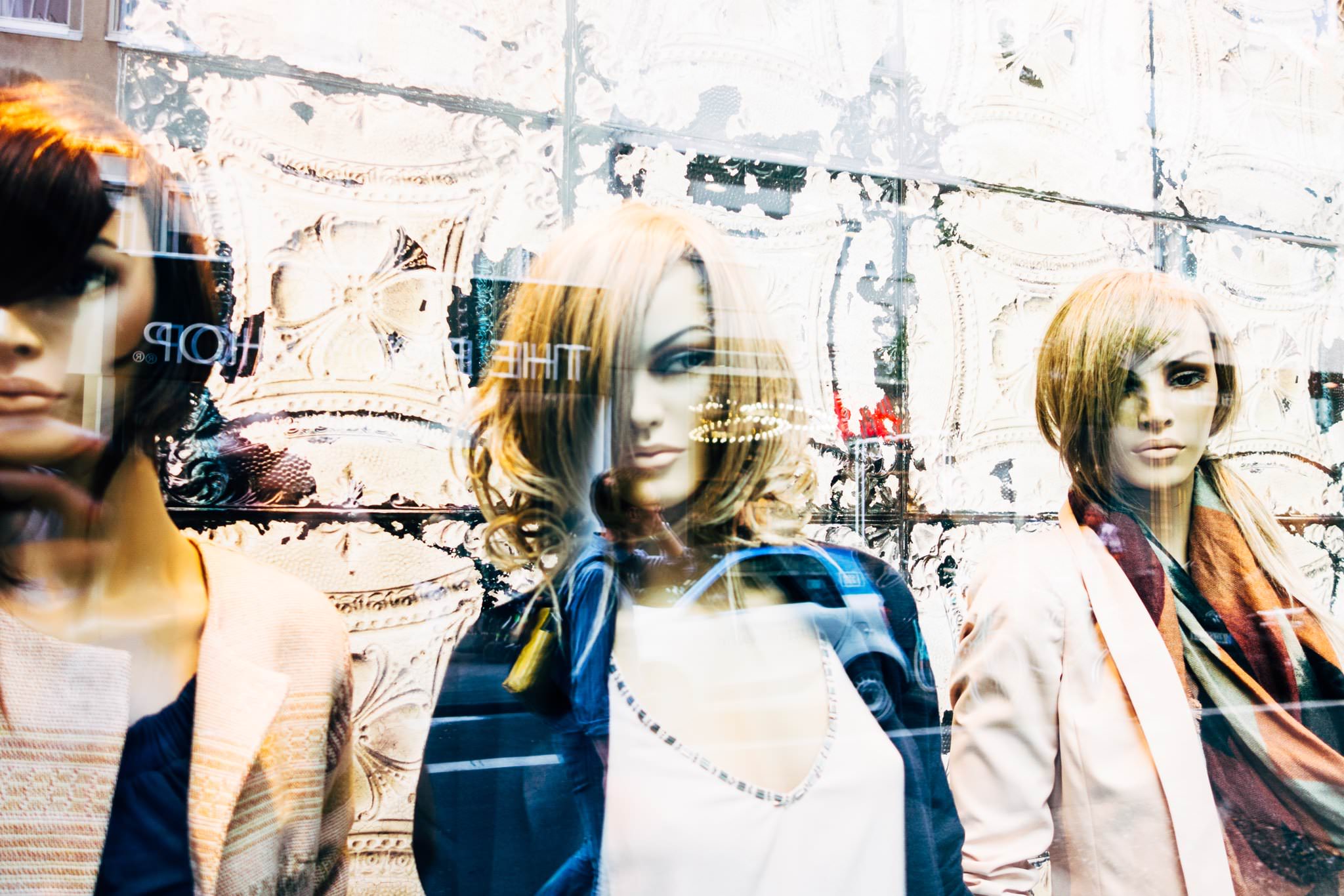 Three mannequins in a shop window.