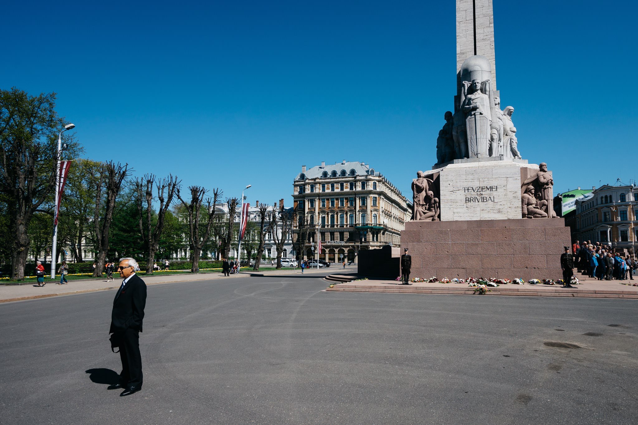 Freedom Monument in Riga, Latvia, with a man in a suit standing in the foreground.