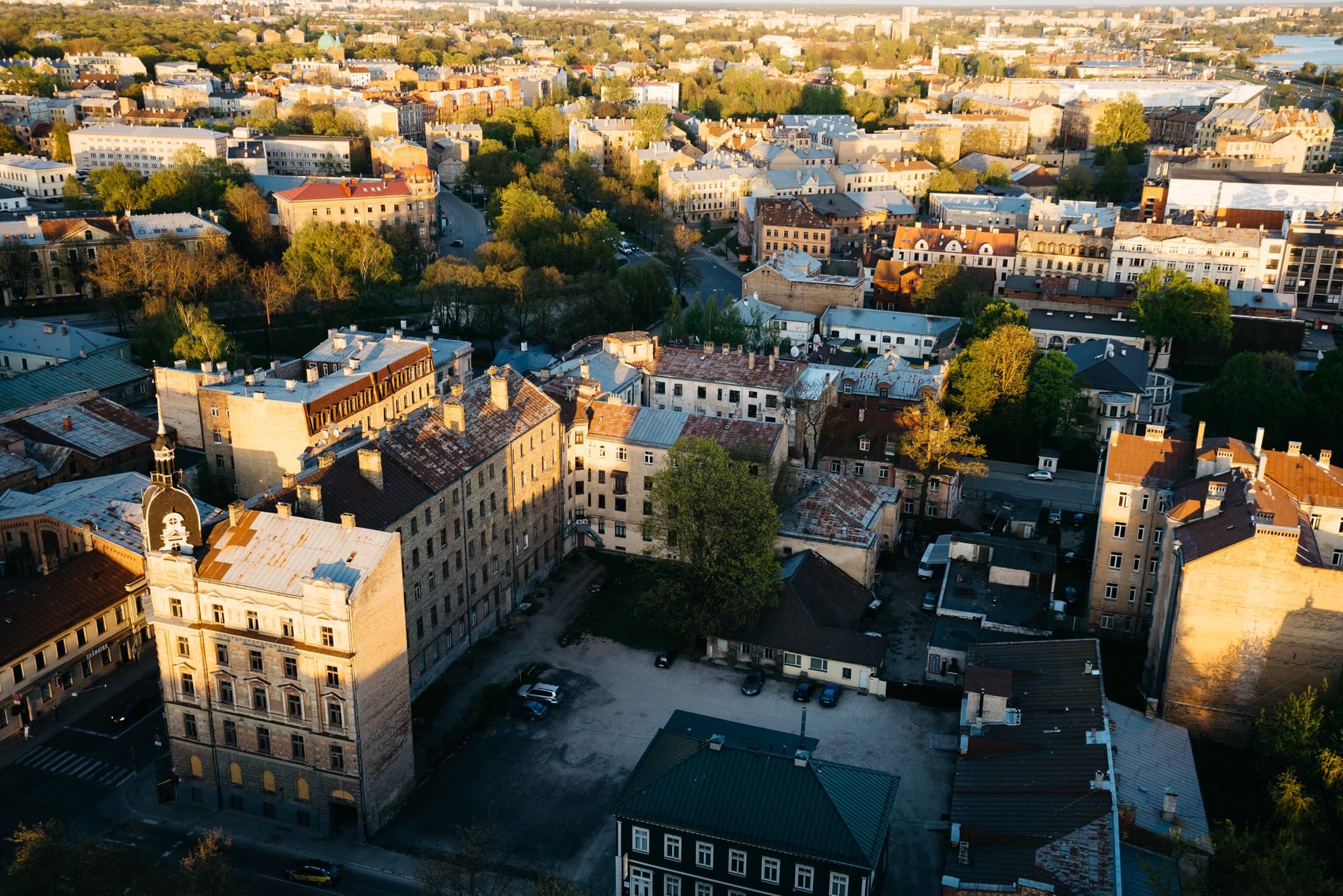 Aerial view of Riga, Latvia, showing a dense cityscape with buildings and trees at sunset.