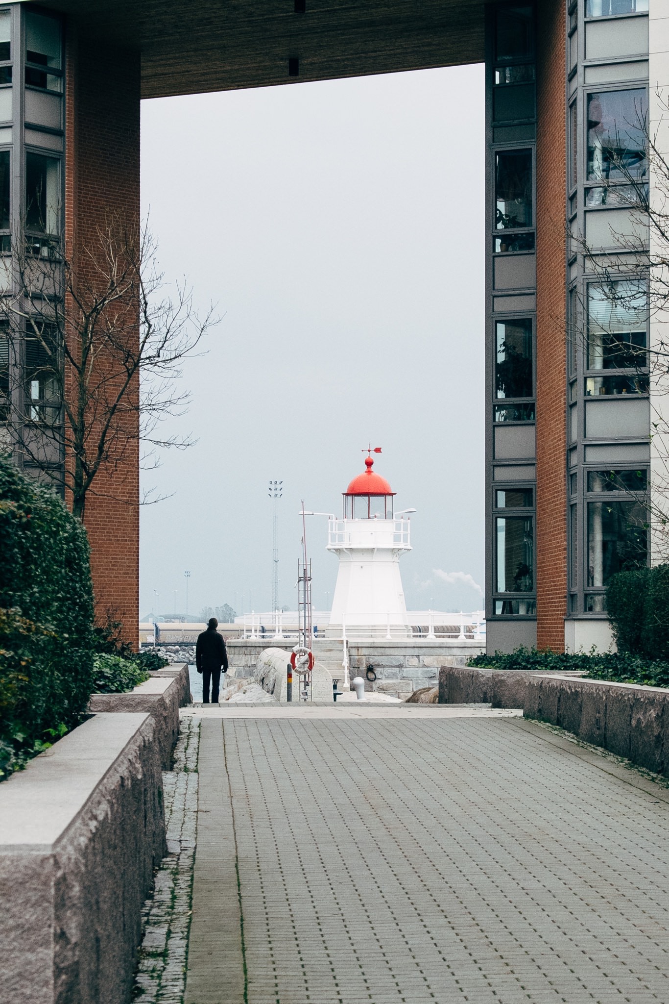 Lighthouse viewed through a walkway between buildings.