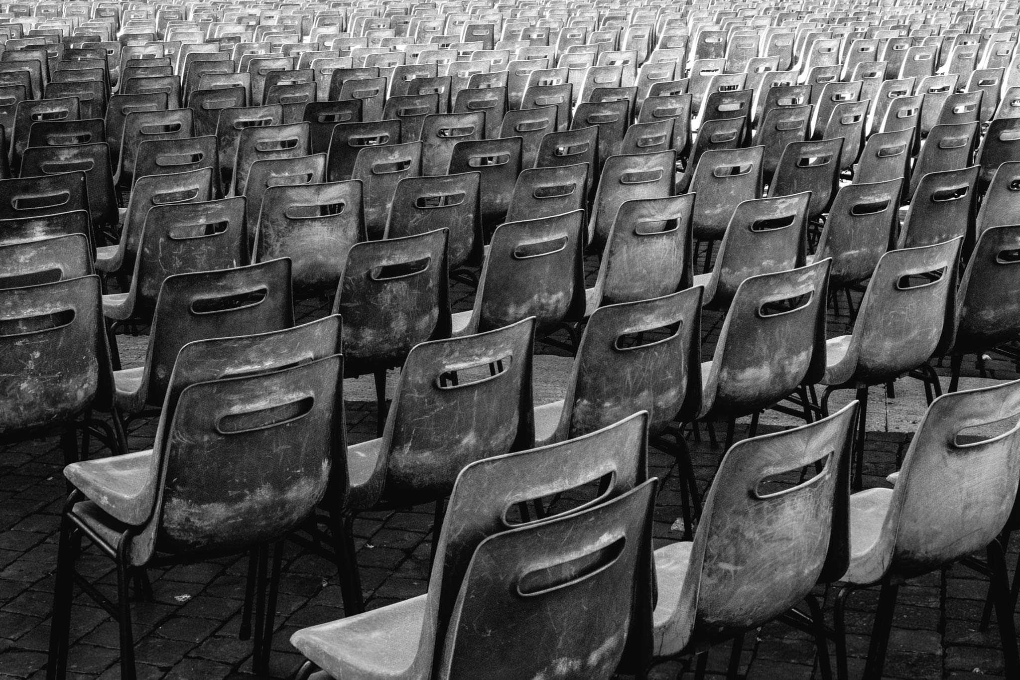 Many weathered gray plastic chairs arranged in rows.