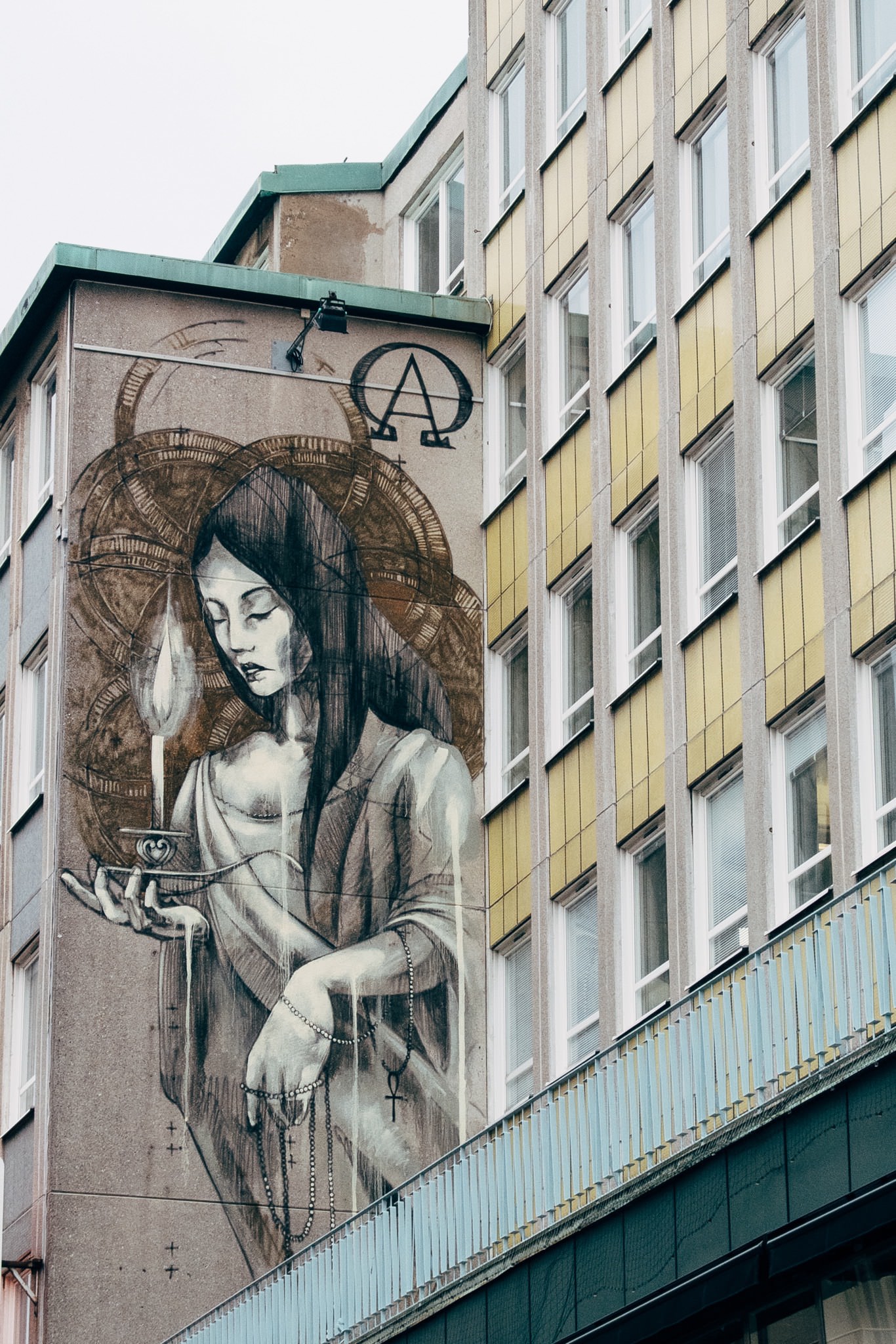Mural of woman holding candle, Alpha and Omega symbols, Malmö.