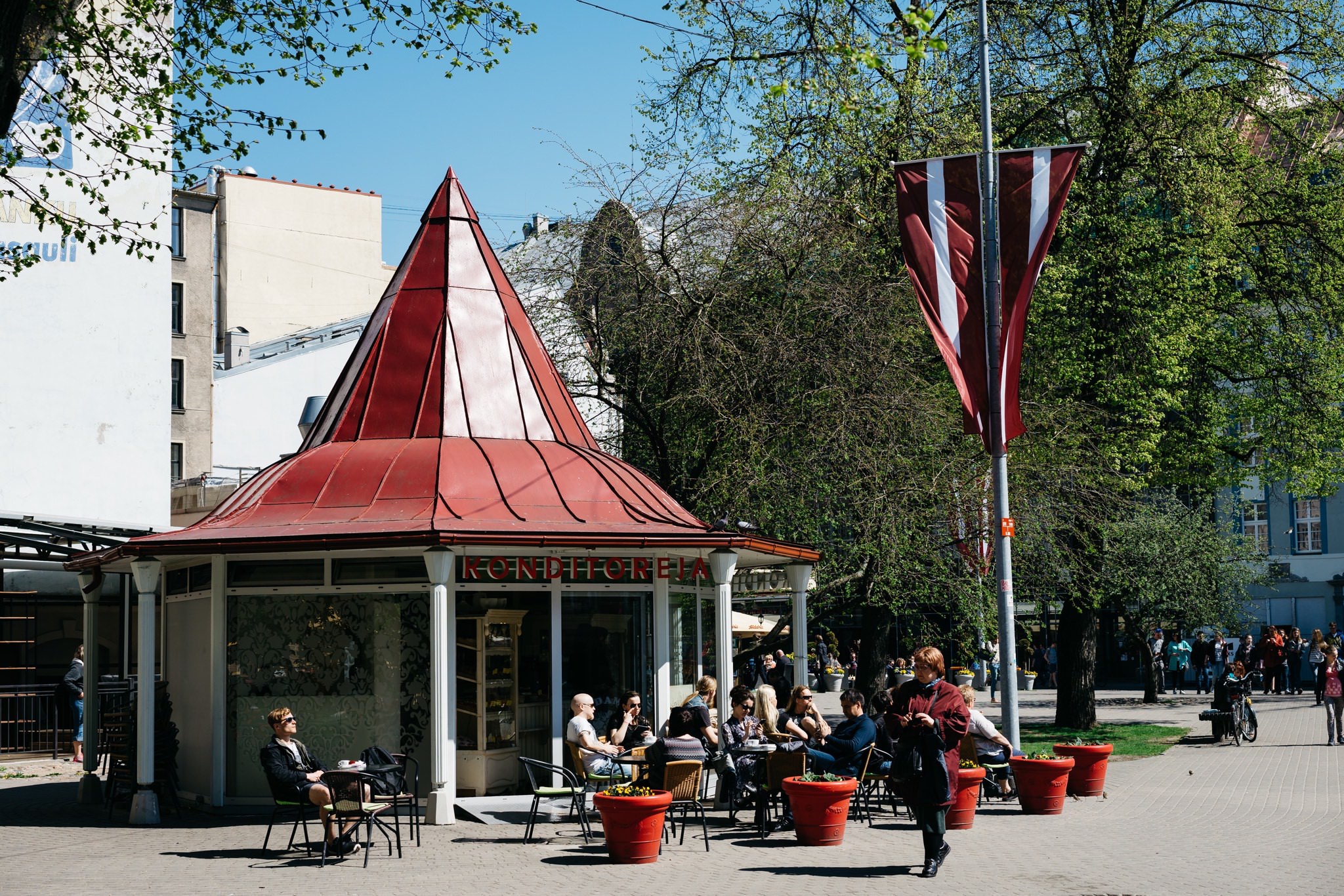 Outdoor cafe in Riga, Latvia, with red roof and patrons seated at tables.