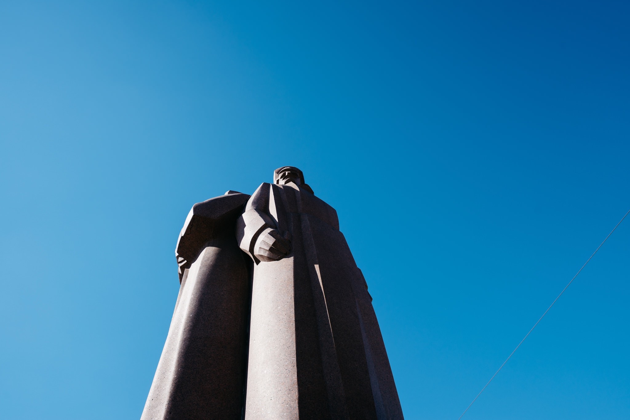 Low-angle view of a large, stone statue against a clear blue sky.