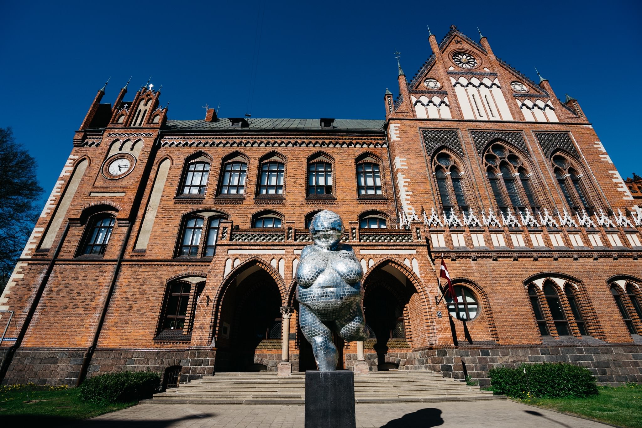 Mirror sculpture in front of brick building in Riga, Latvia.
