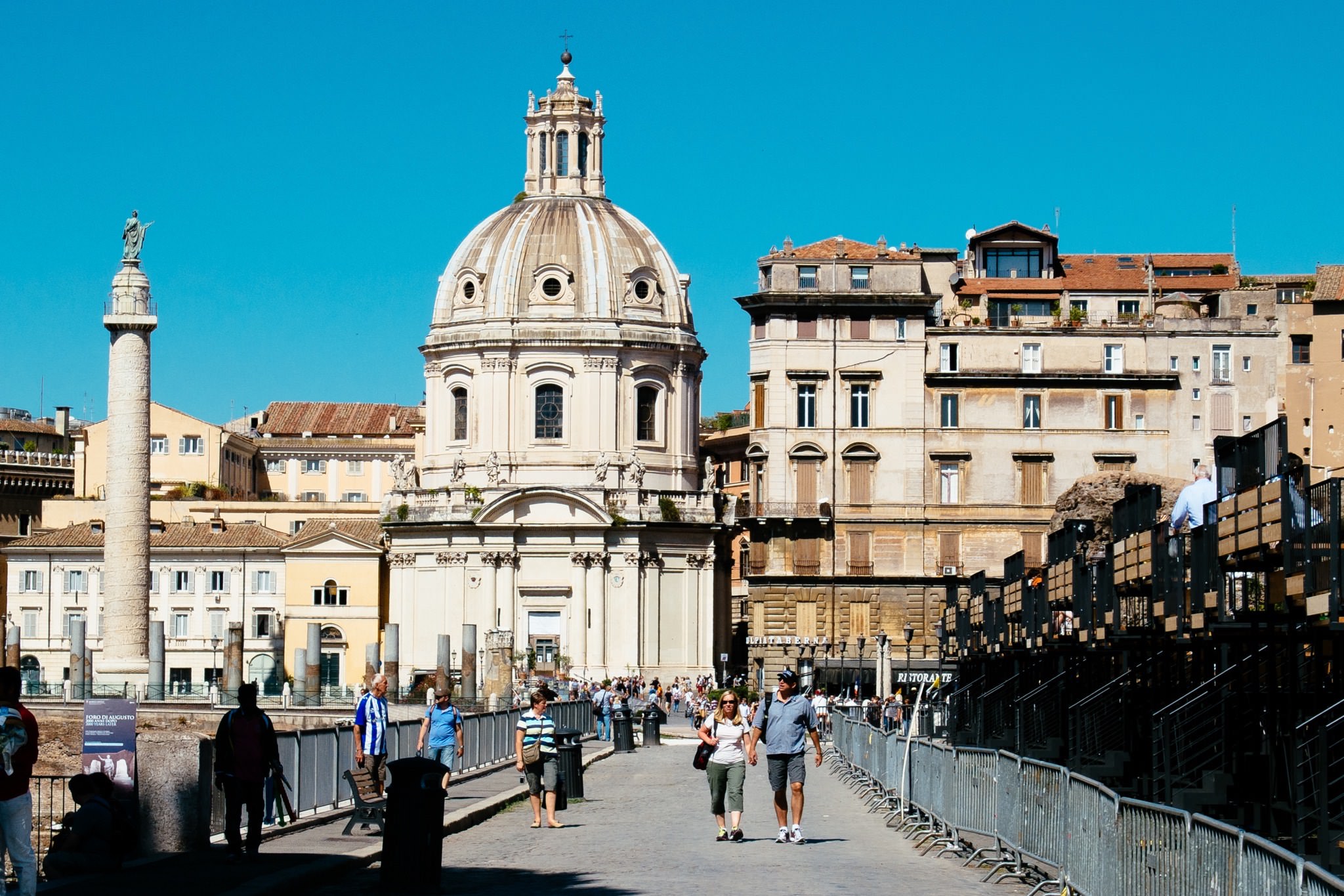 Rome, Italy: Tourists walking past a church and ancient columns.