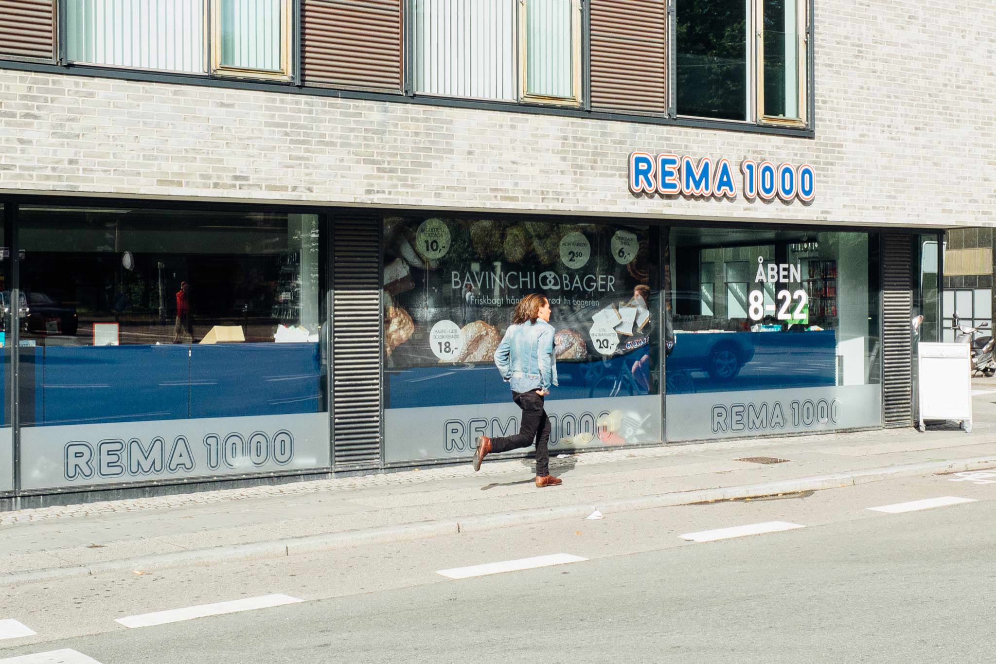 Person running past a Rema 1000 supermarket.