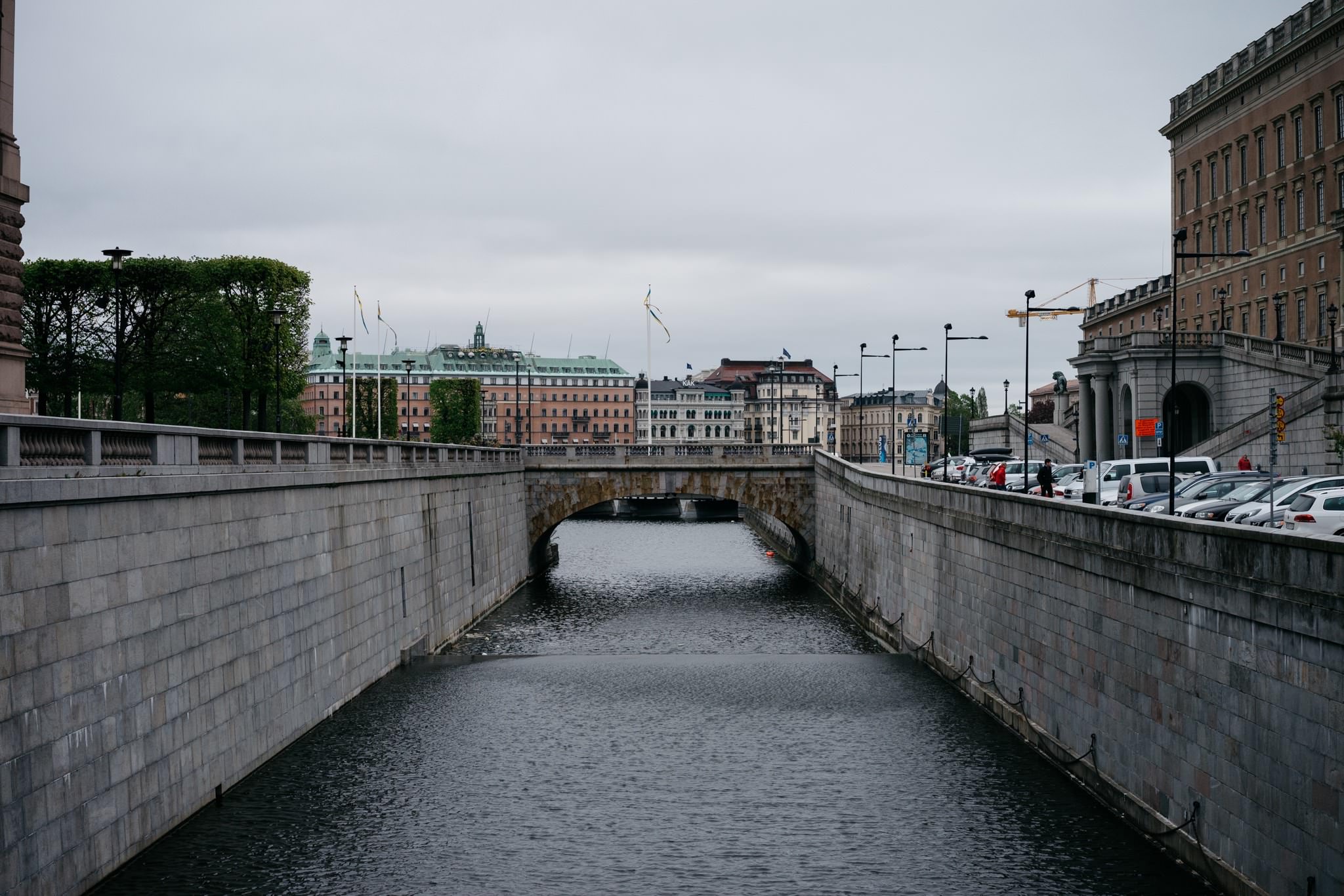 Stockholm canal with stone walls and bridge, city buildings in background.