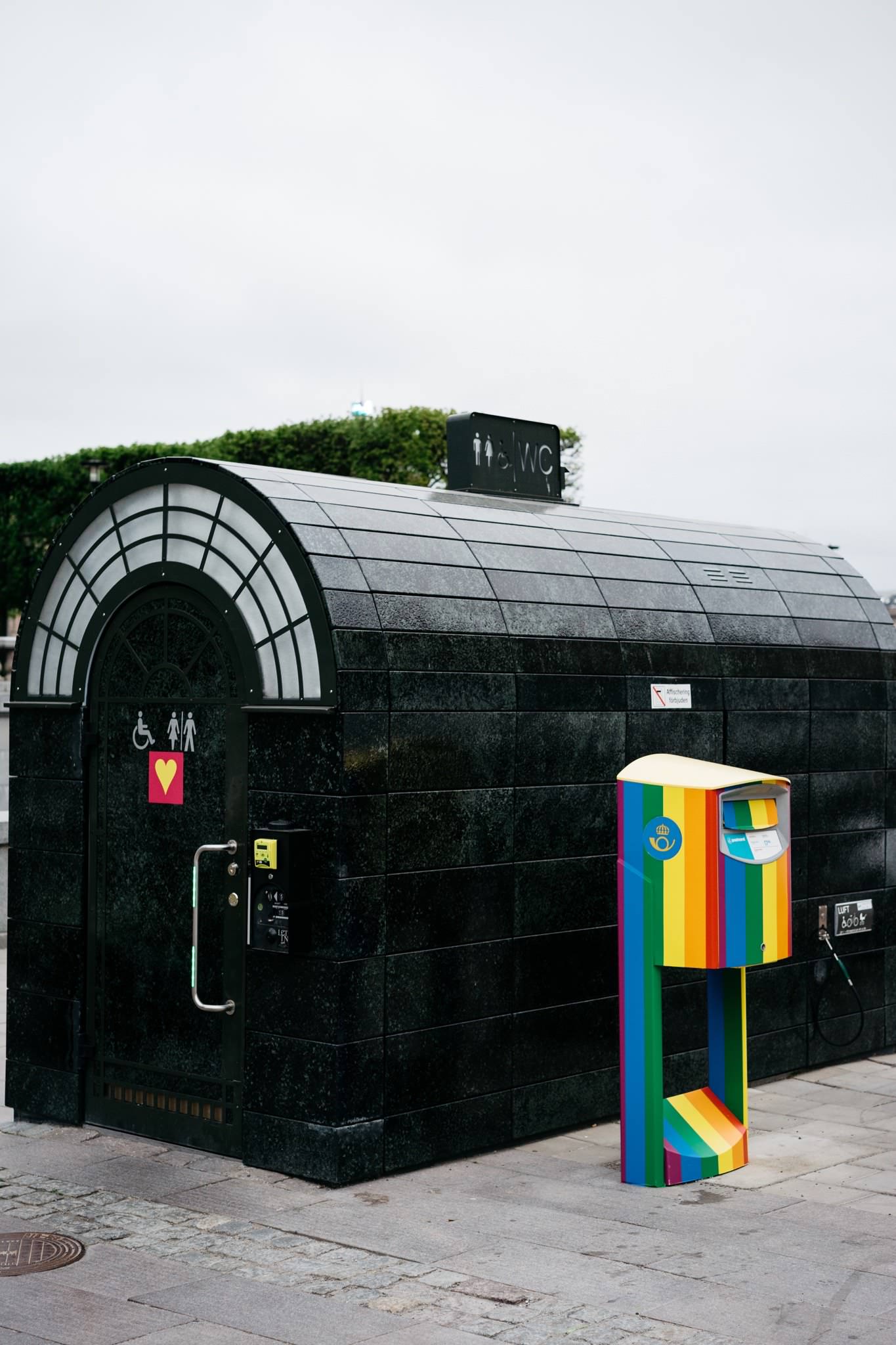 Public restroom in Stockholm with a rainbow-colored postal box.