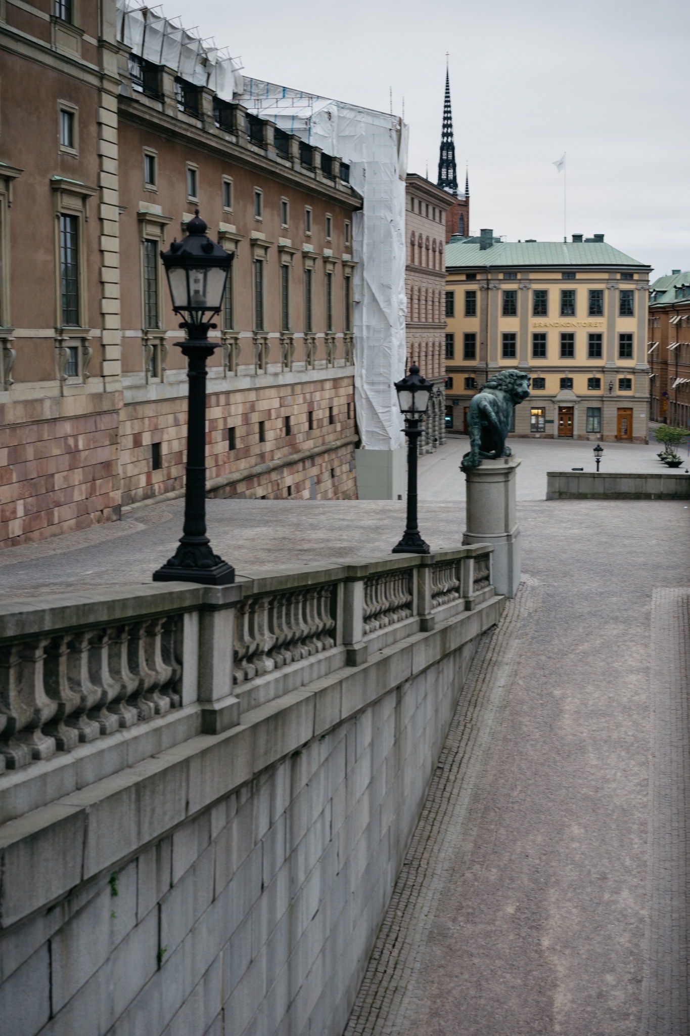 Stockholm street scene with stone lion statue, lampposts, and historic buildings.