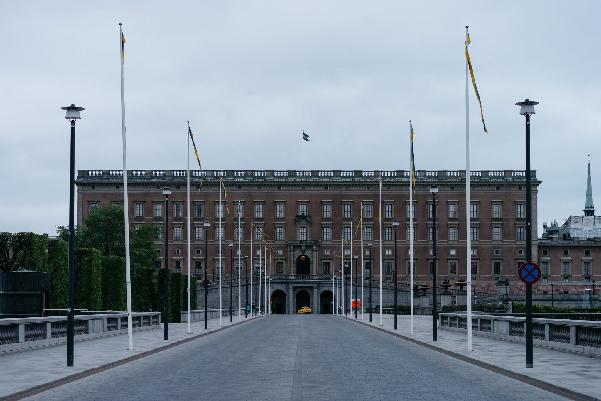 Stockholm Palace with Swedish flags on a cloudy day.