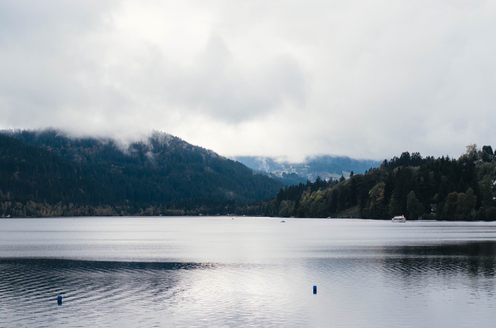 Titisee lake in the Black Forest, Germany, with a boat and fog over the mountains.