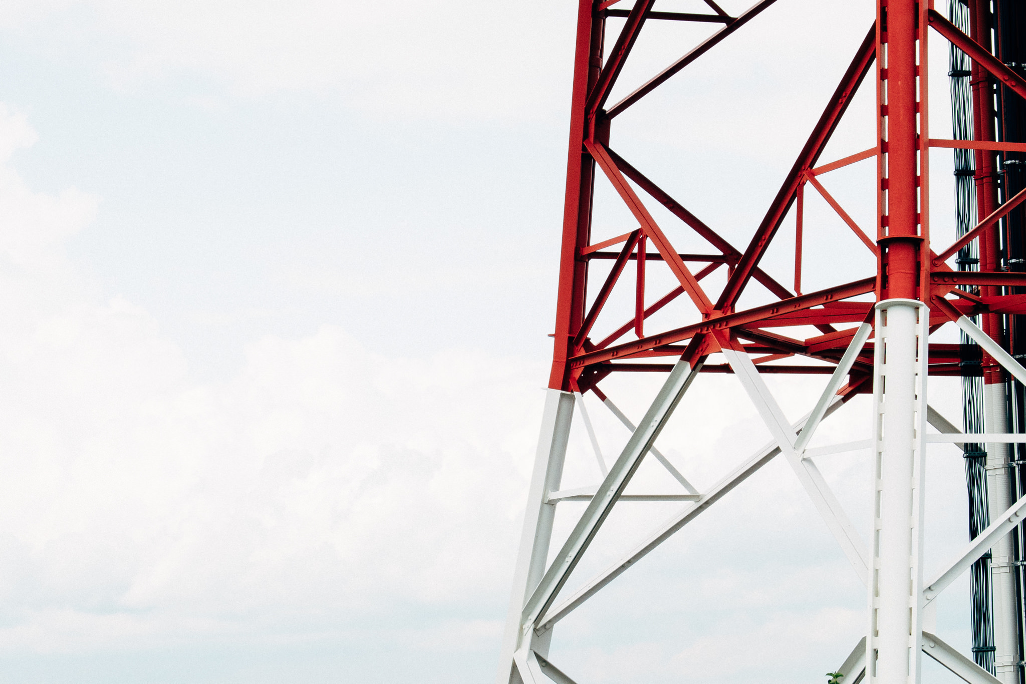 Close-up of a red and white metal tower against a cloudy sky.