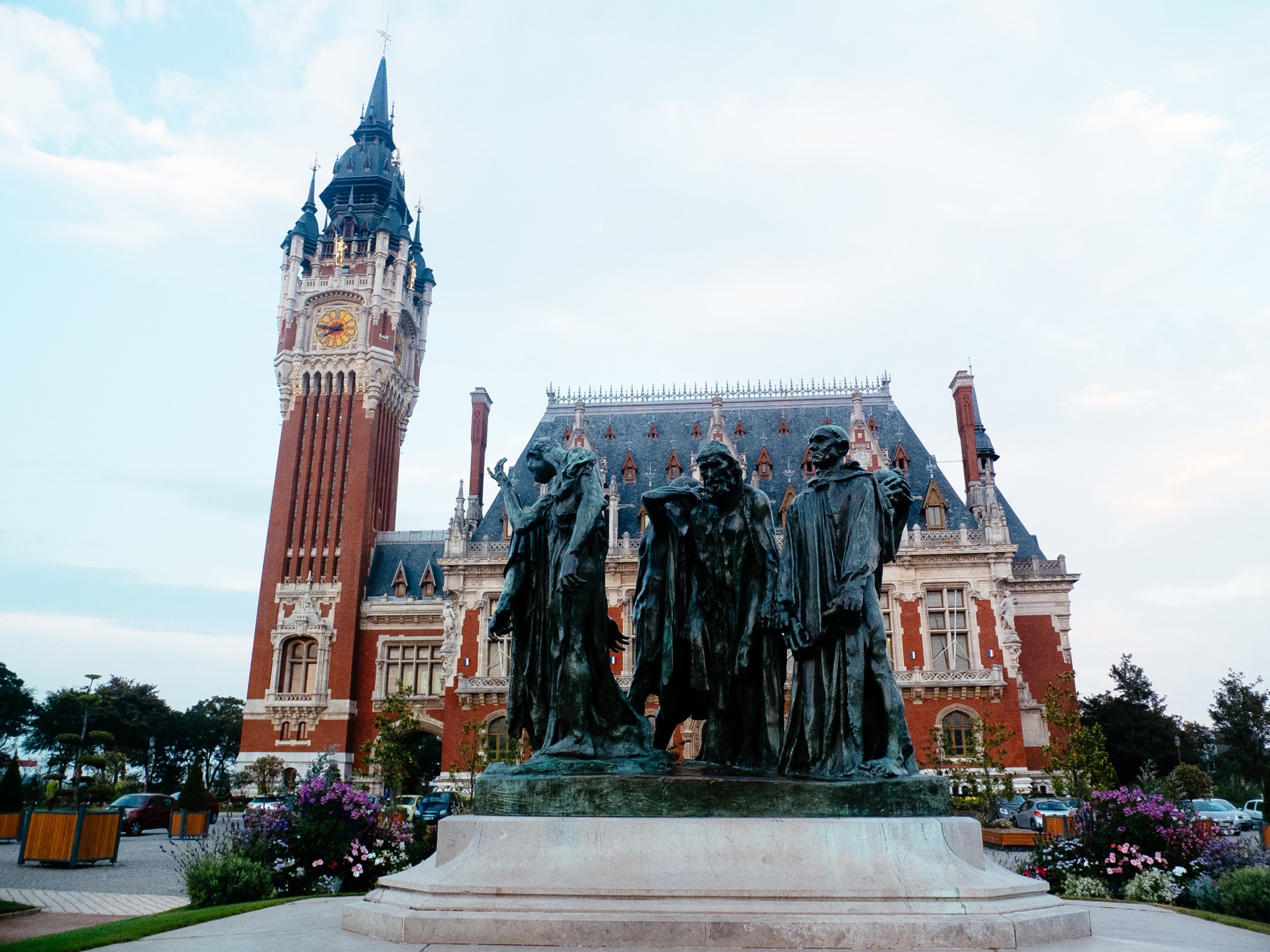 Calais town hall with a bronze statue in front.