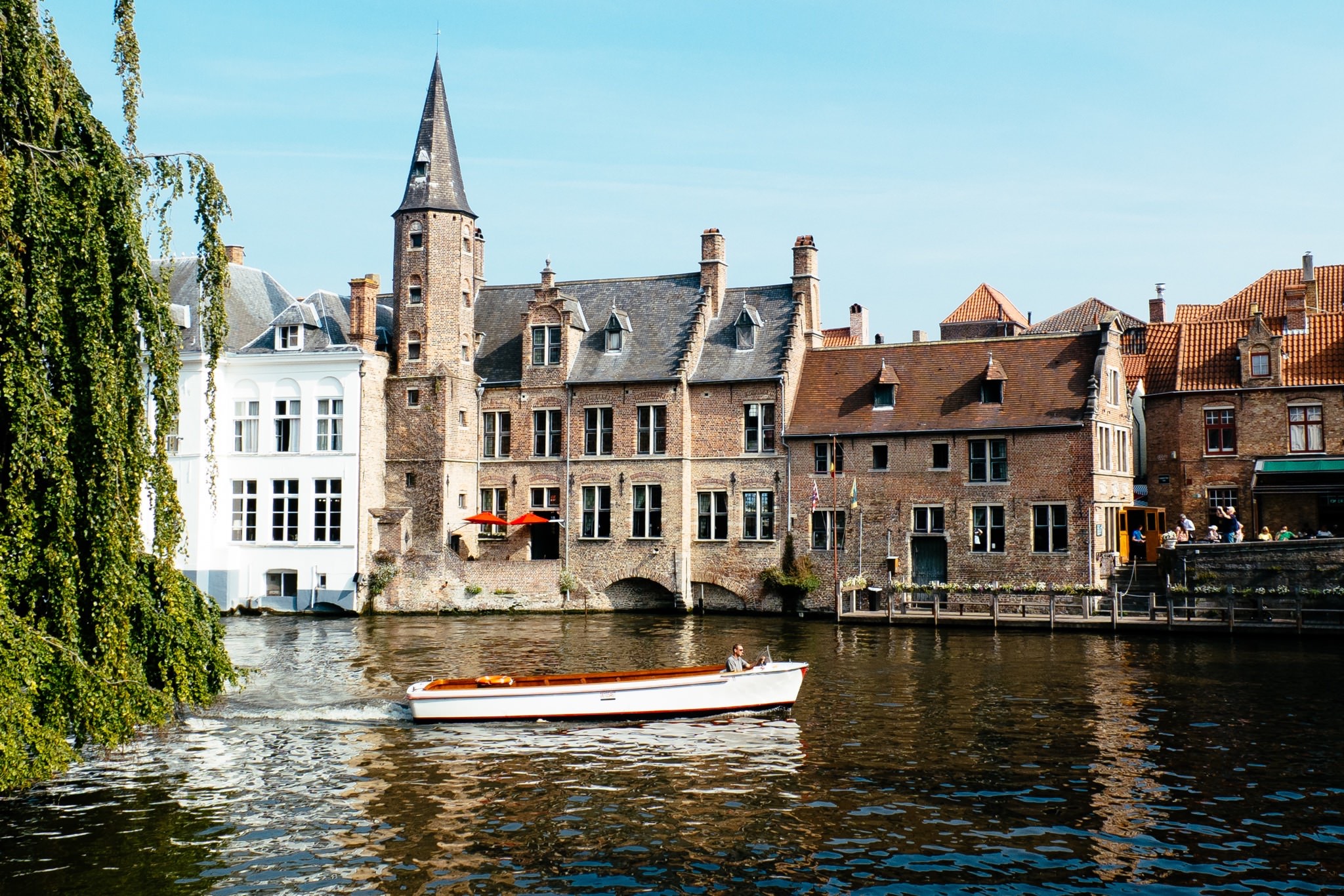 Boat on Bruges canal with historic buildings.