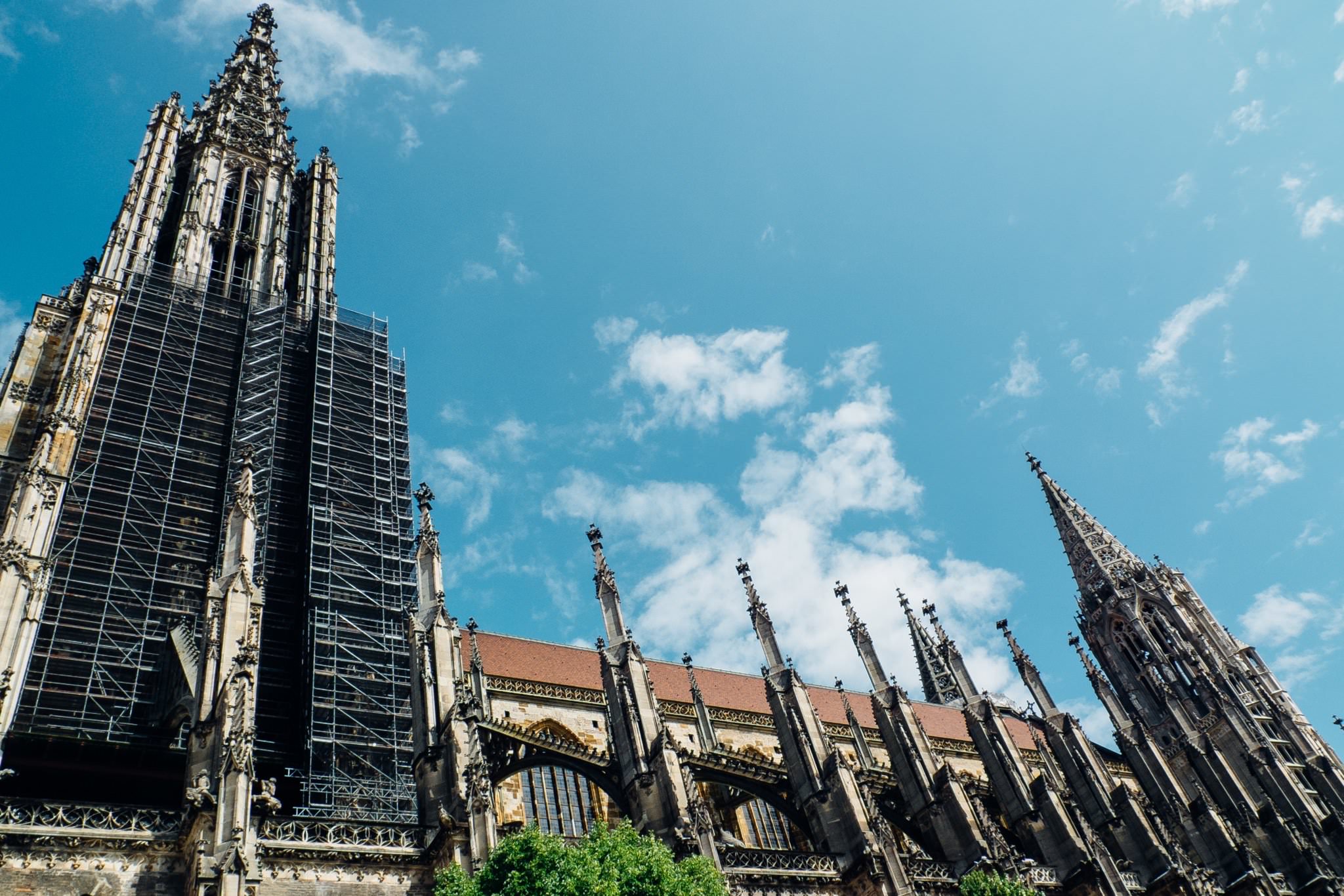 Ulm Minster under blue sky, partially covered in scaffolding.