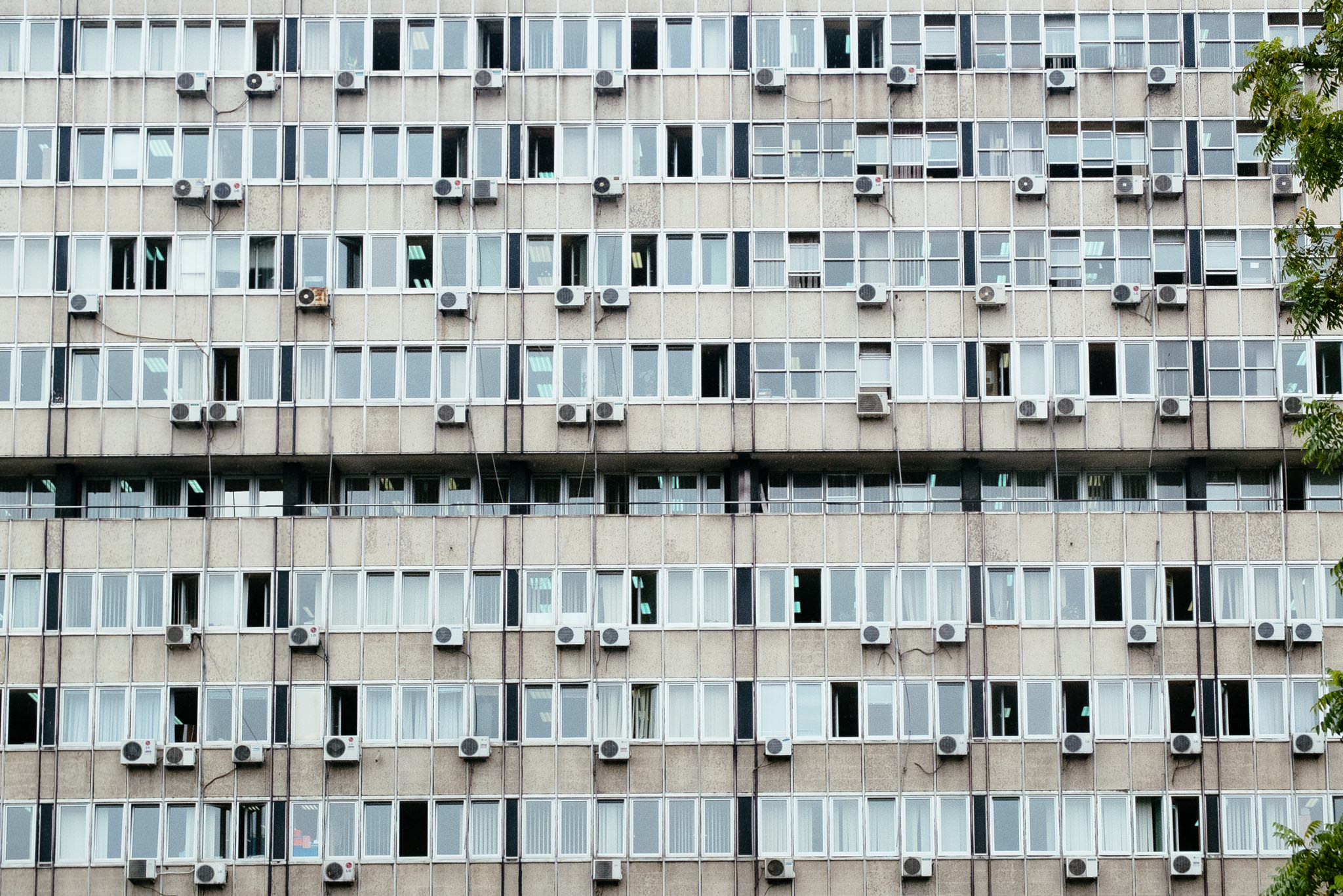 A beige multi-story building with many windows and air conditioning units.