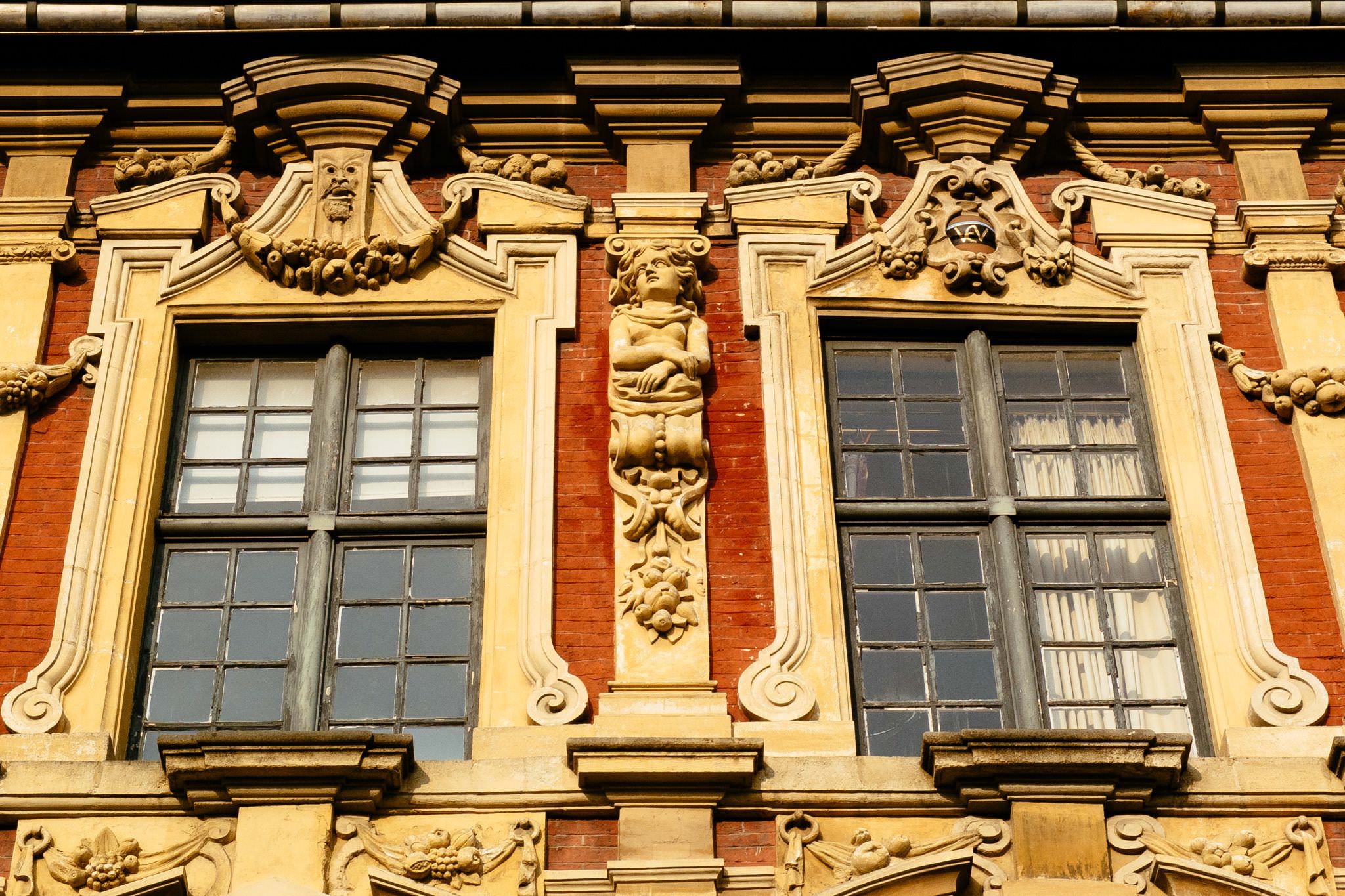 Ornate building facade with two multi-paned windows and decorative carvings.