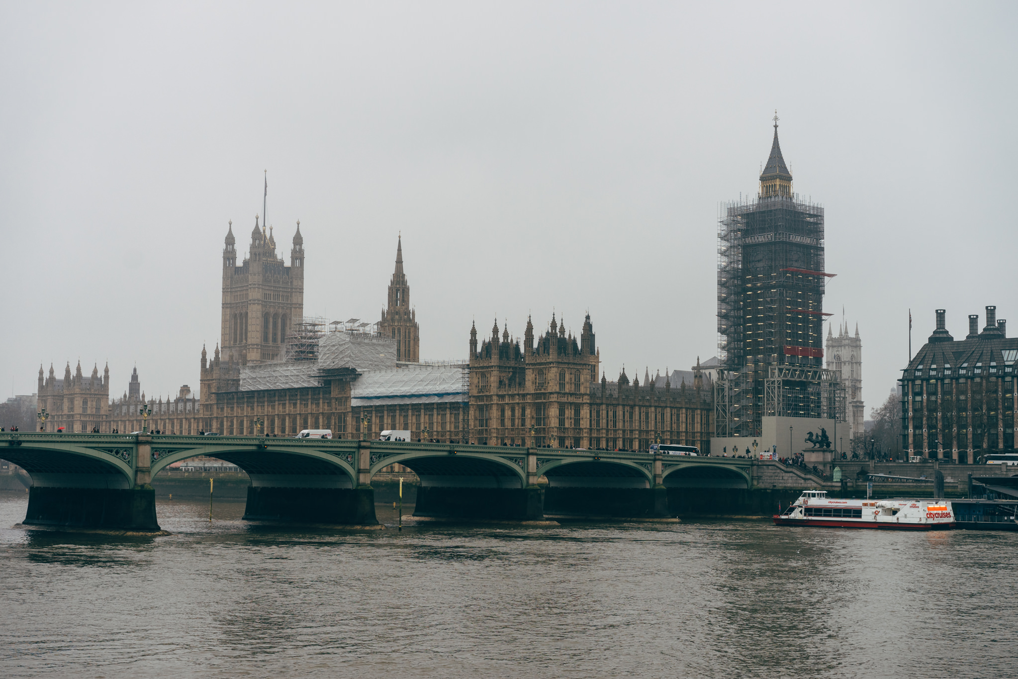Westminster Palace and Big Ben under construction, viewed from across the Thames River.