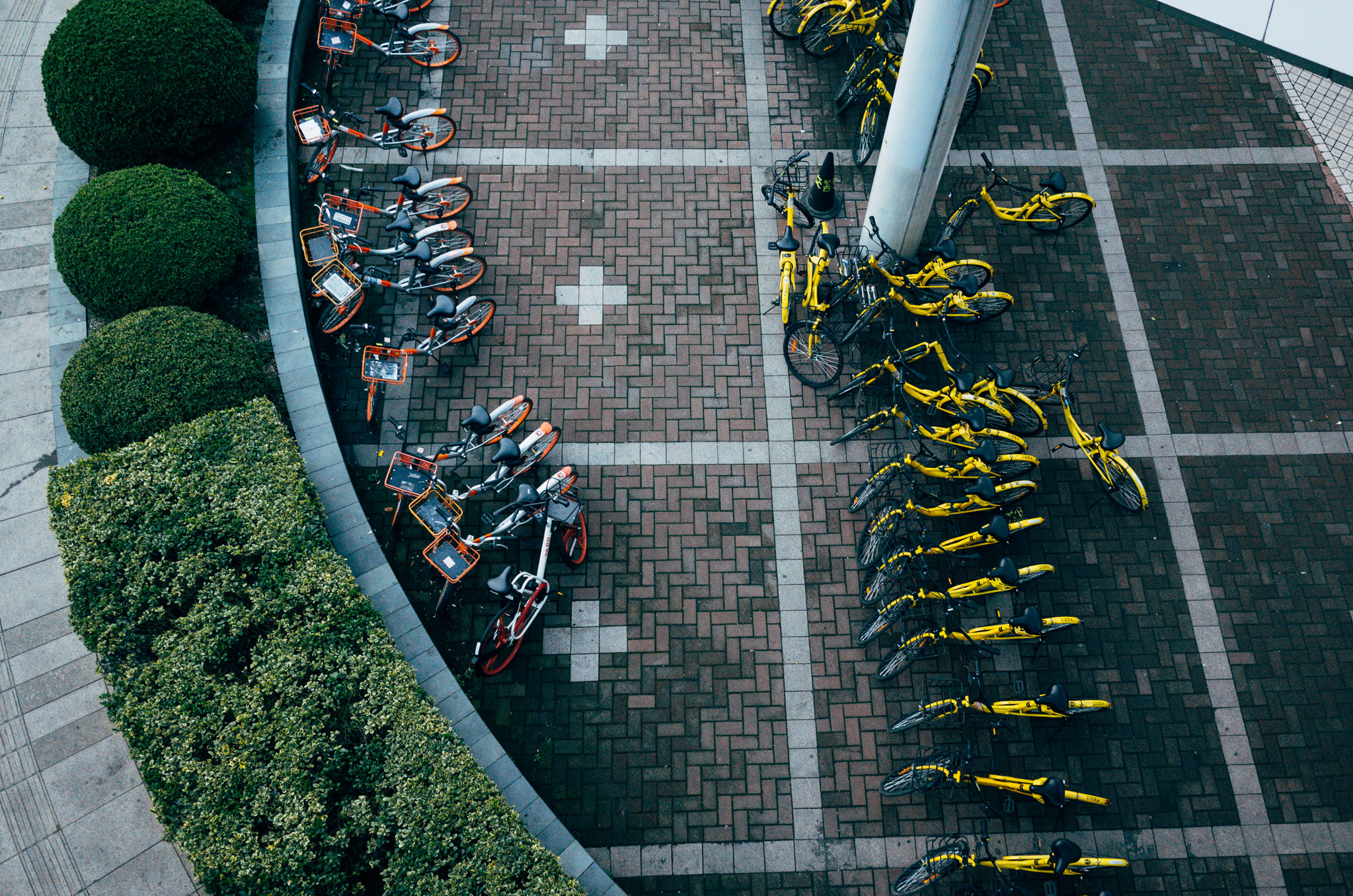 Aerial view of bike-sharing station in Shanghai, China with orange and yellow bikes.