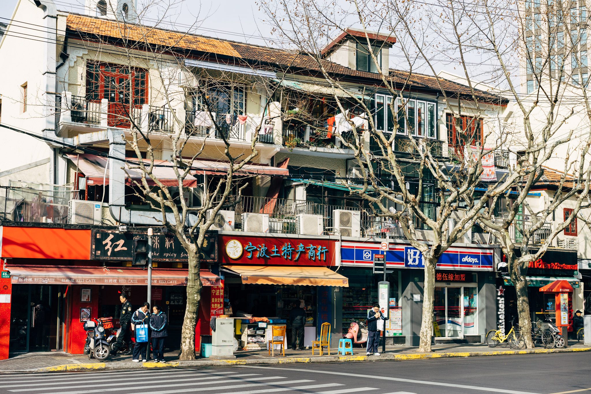 Shanghai street scene with multi-story buildings, shops, and bare trees.