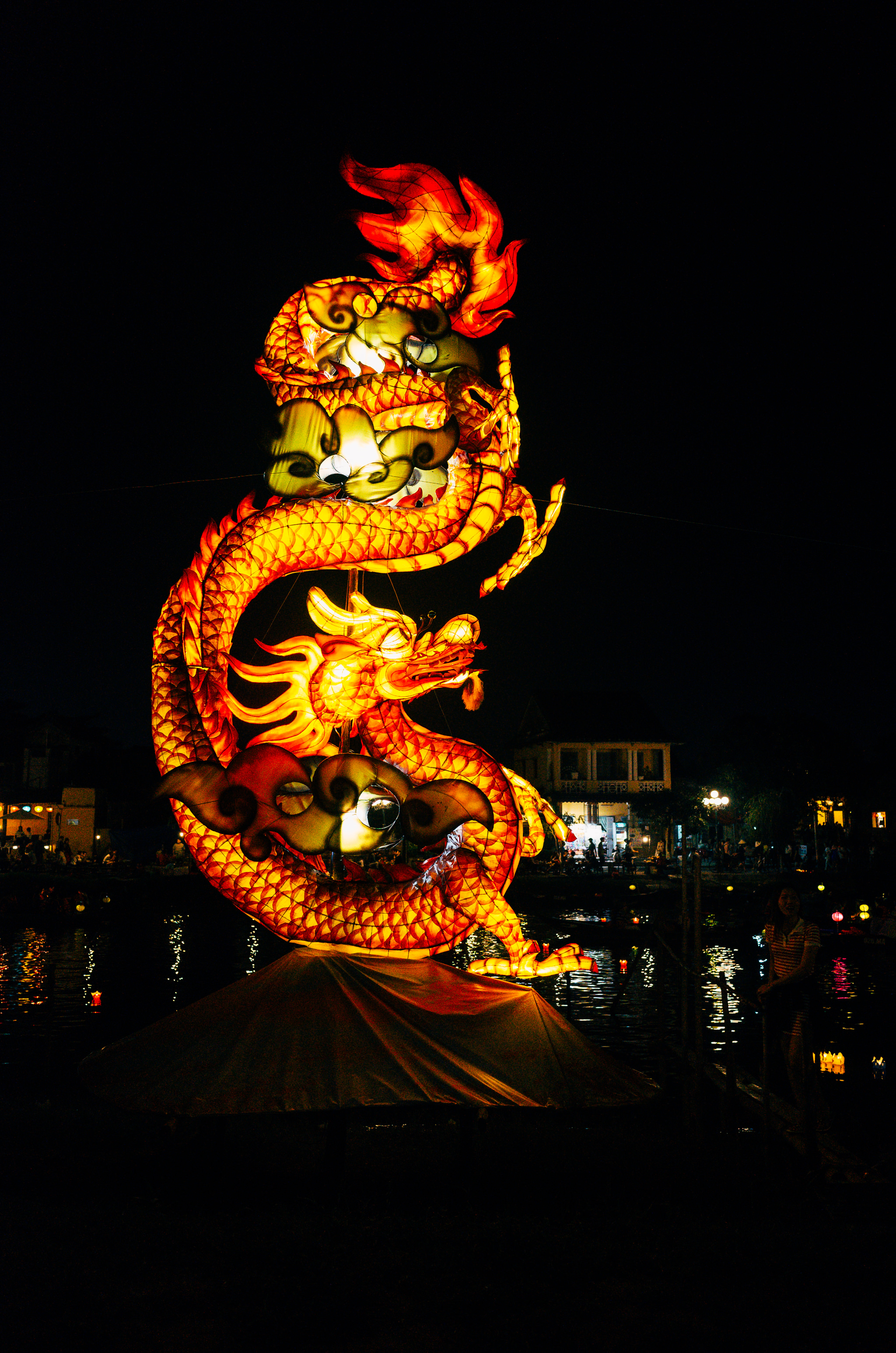 Illuminated dragon lantern on a boat at night.