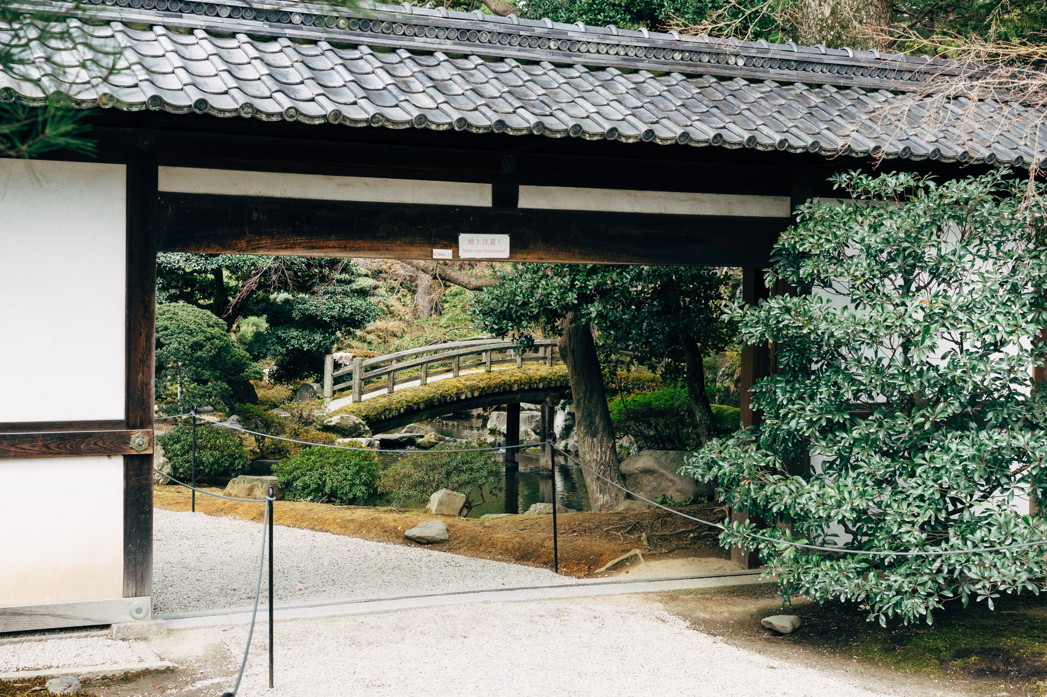 Wooden gate to a Japanese garden with a small bridge and pond.