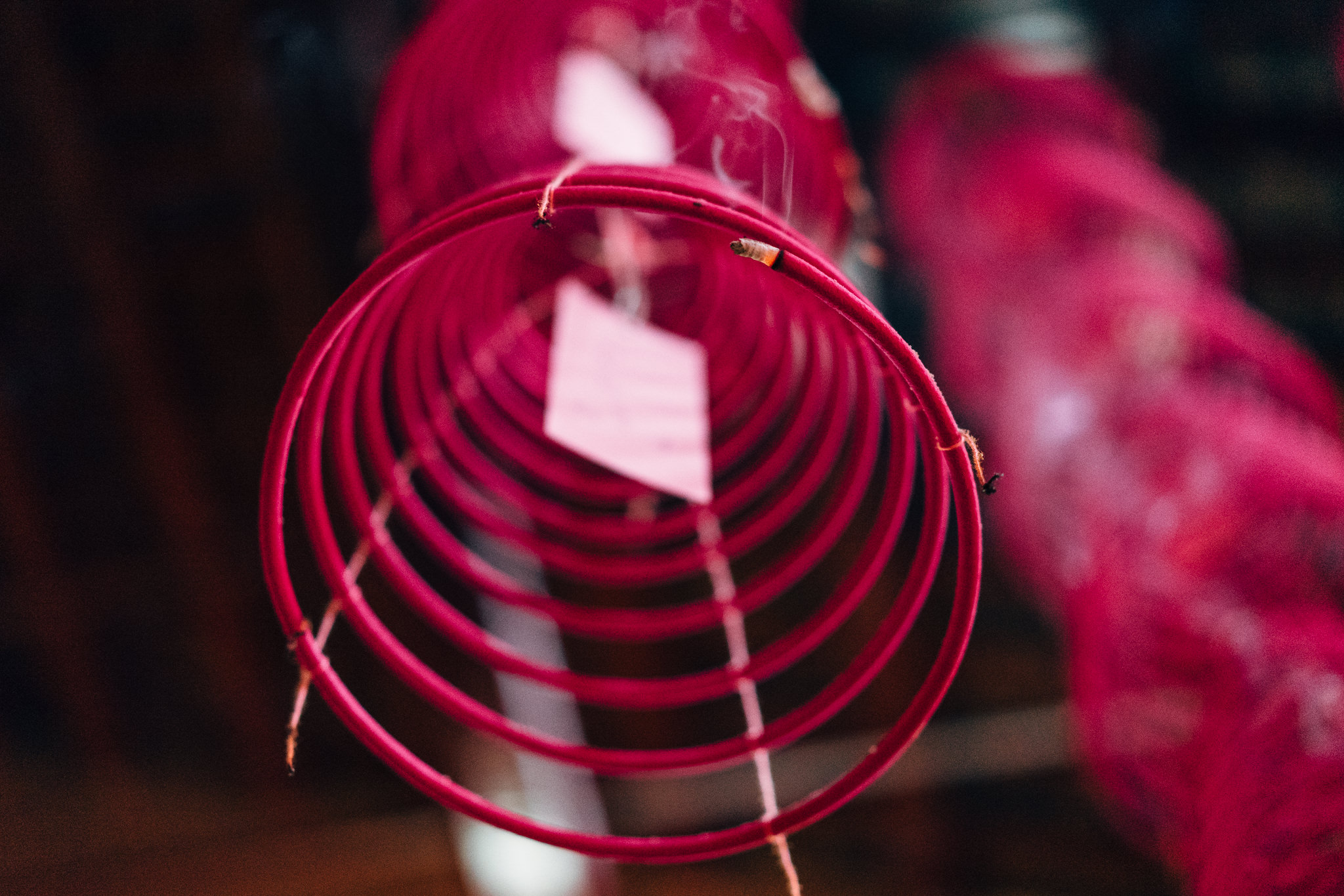 Close-up of a burning pink spiral incense coil.