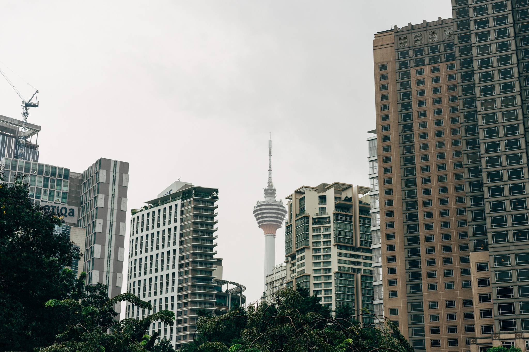 Kuala Lumpur Tower viewed from between modern high-rise buildings.