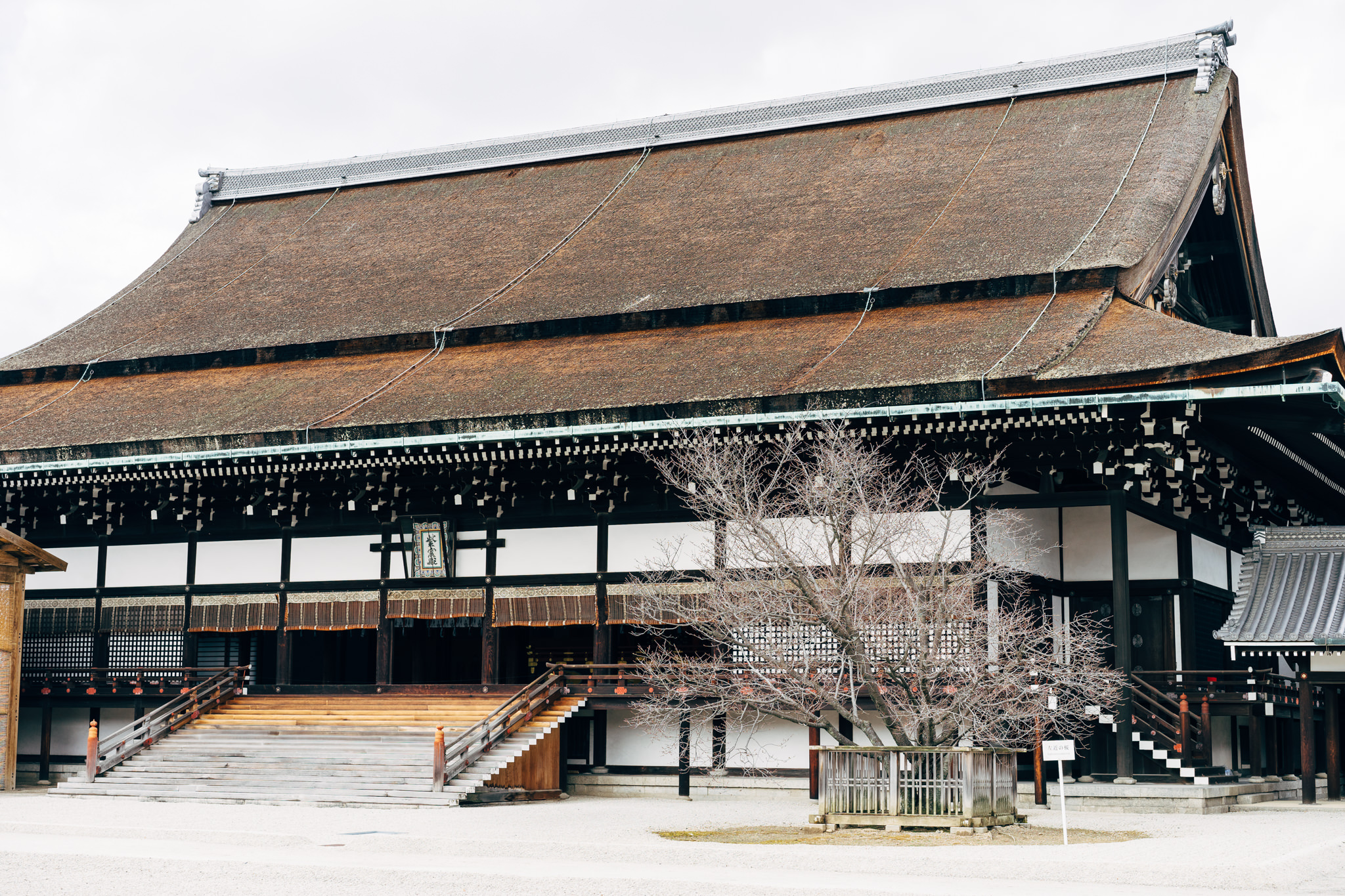 Kyoto Gosho Imperial Palace building with a large, brown, thatched roof and wooden staircase.