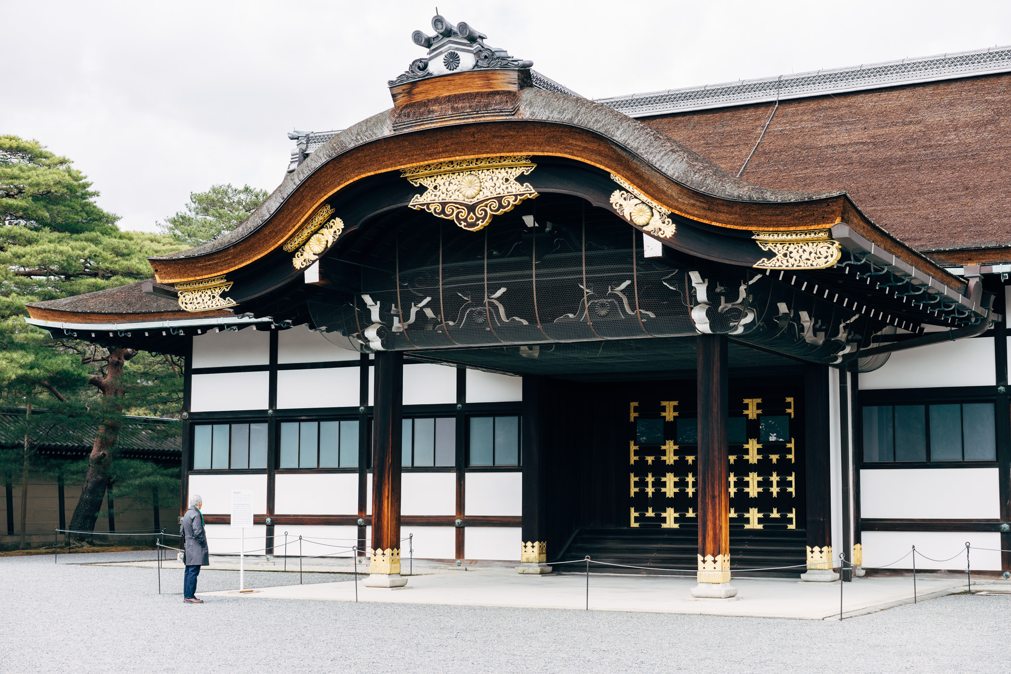 Kyoto Imperial Palace entrance with ornate roof and a person standing in front.