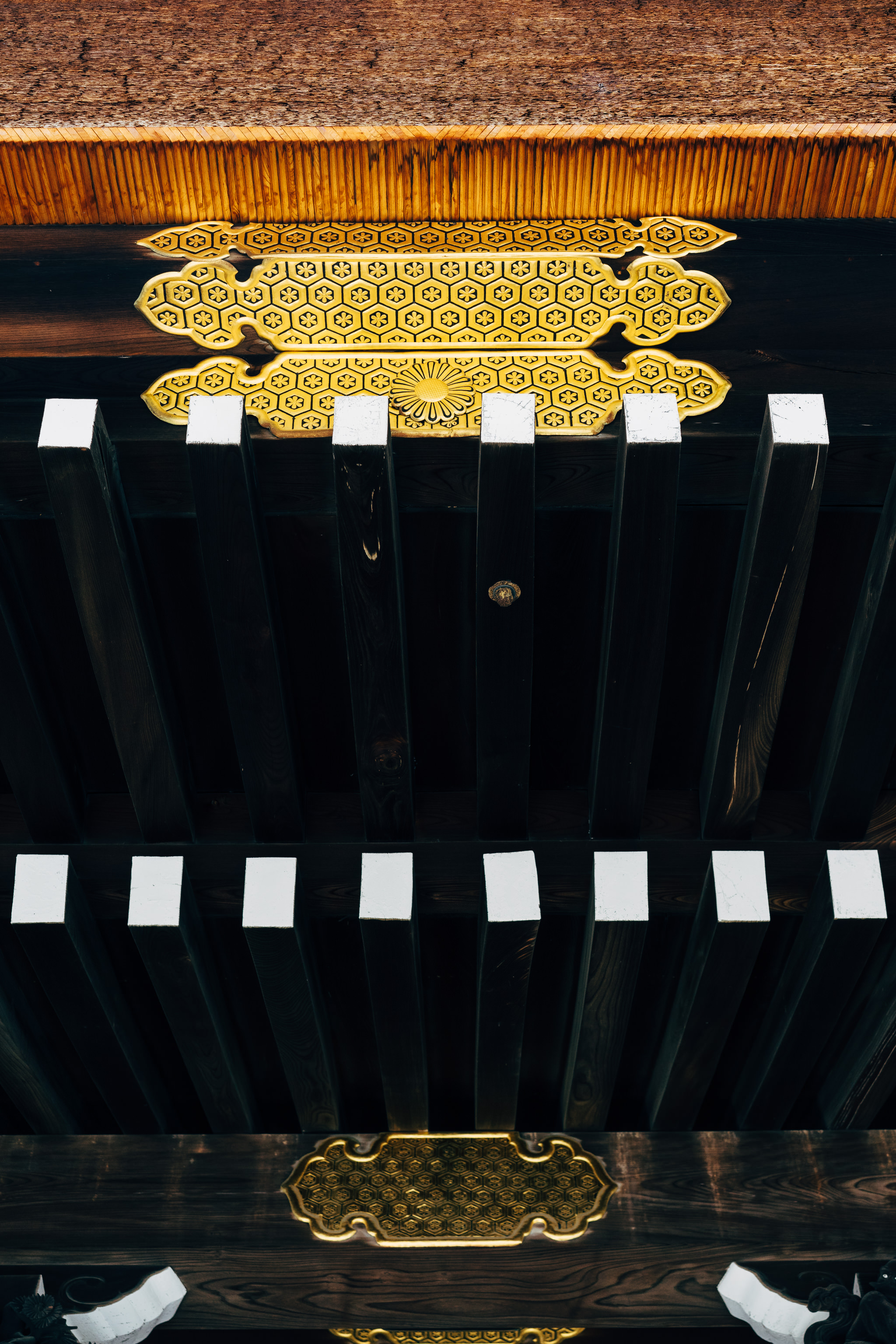 Close-up of ornate gold and dark wood details on a Kyoto Imperial Palace ceiling.