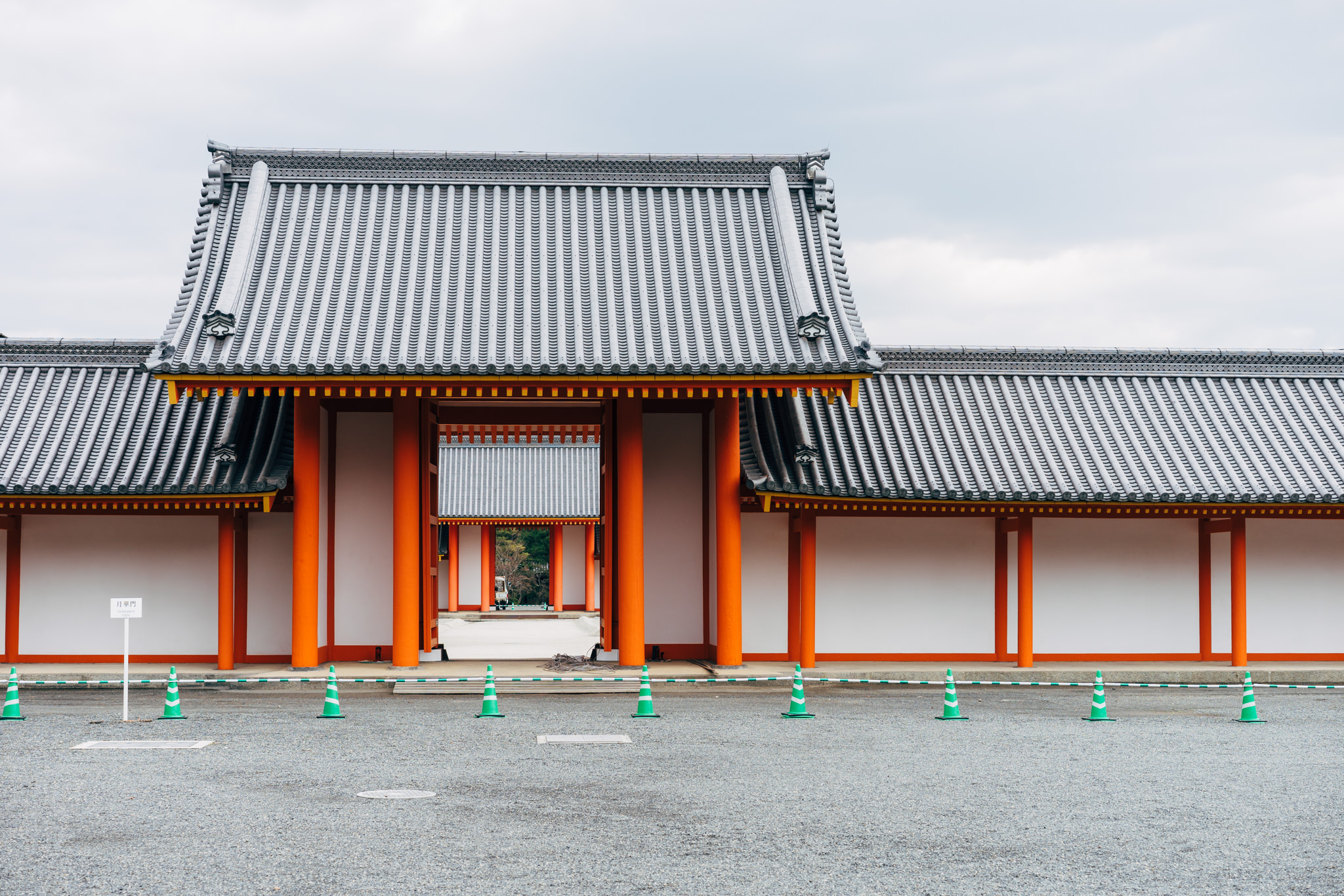 Kyoto Imperial Palace gate with orange pillars and grey tiled roofs.