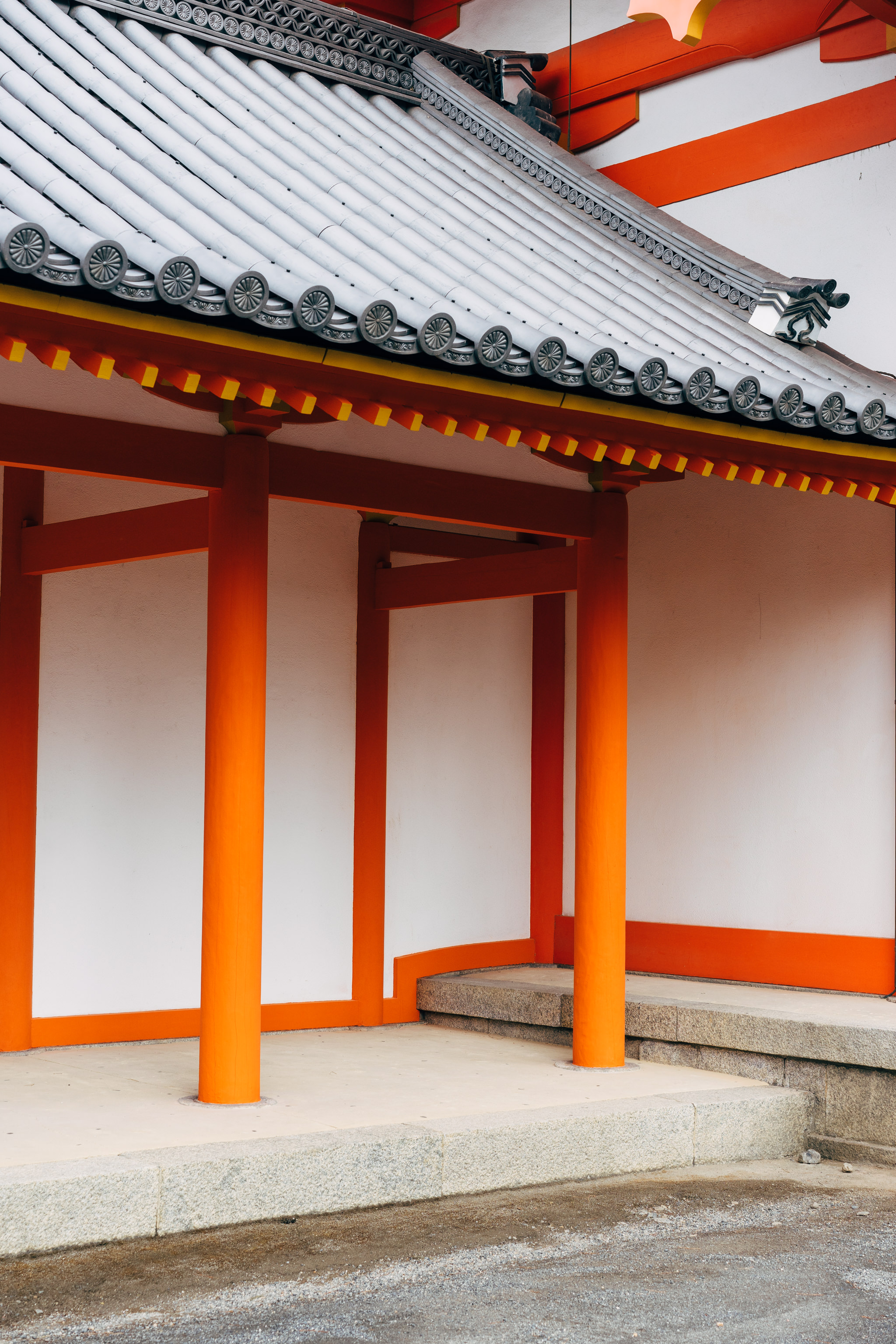 Kyoto Imperial Palace building detail: grey tiled roof, orange pillars, and white walls.