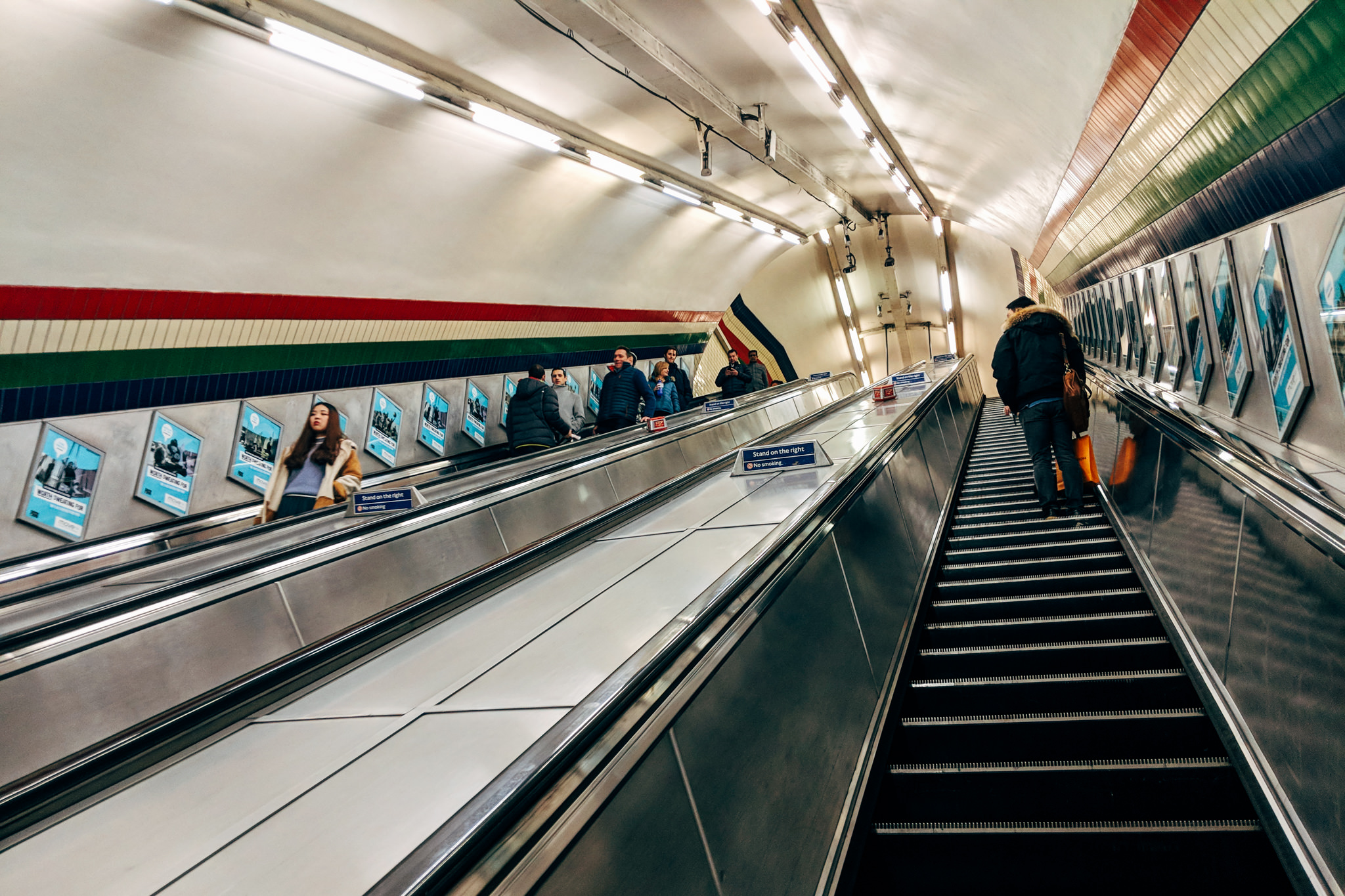 Long escalator in a London subway station with people riding up and down.