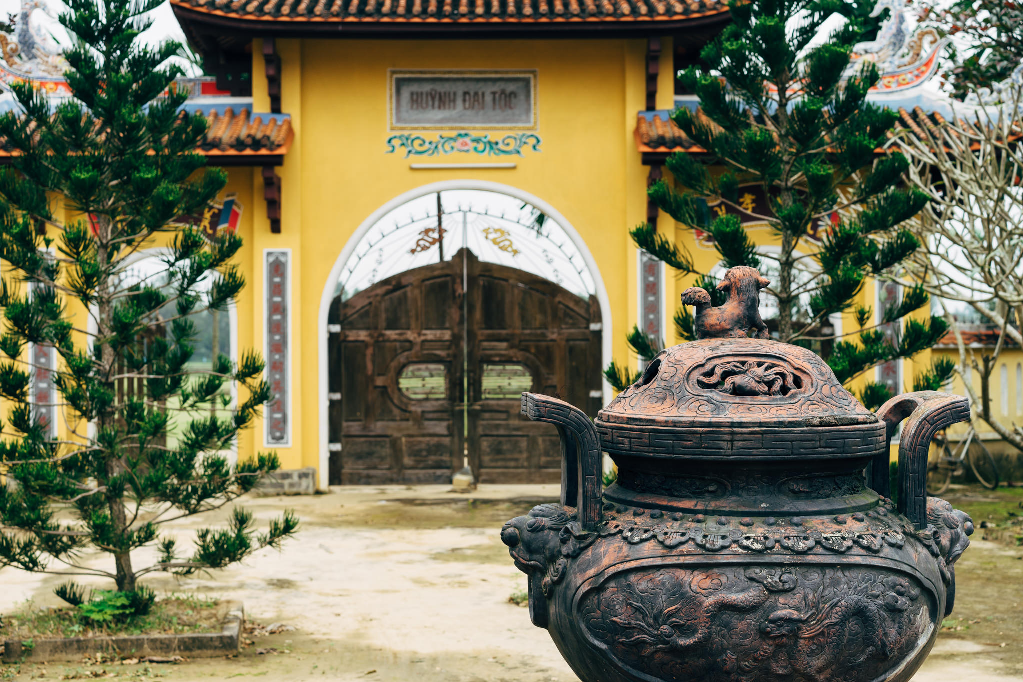 Ornate incense burner in front of a yellow temple gate.