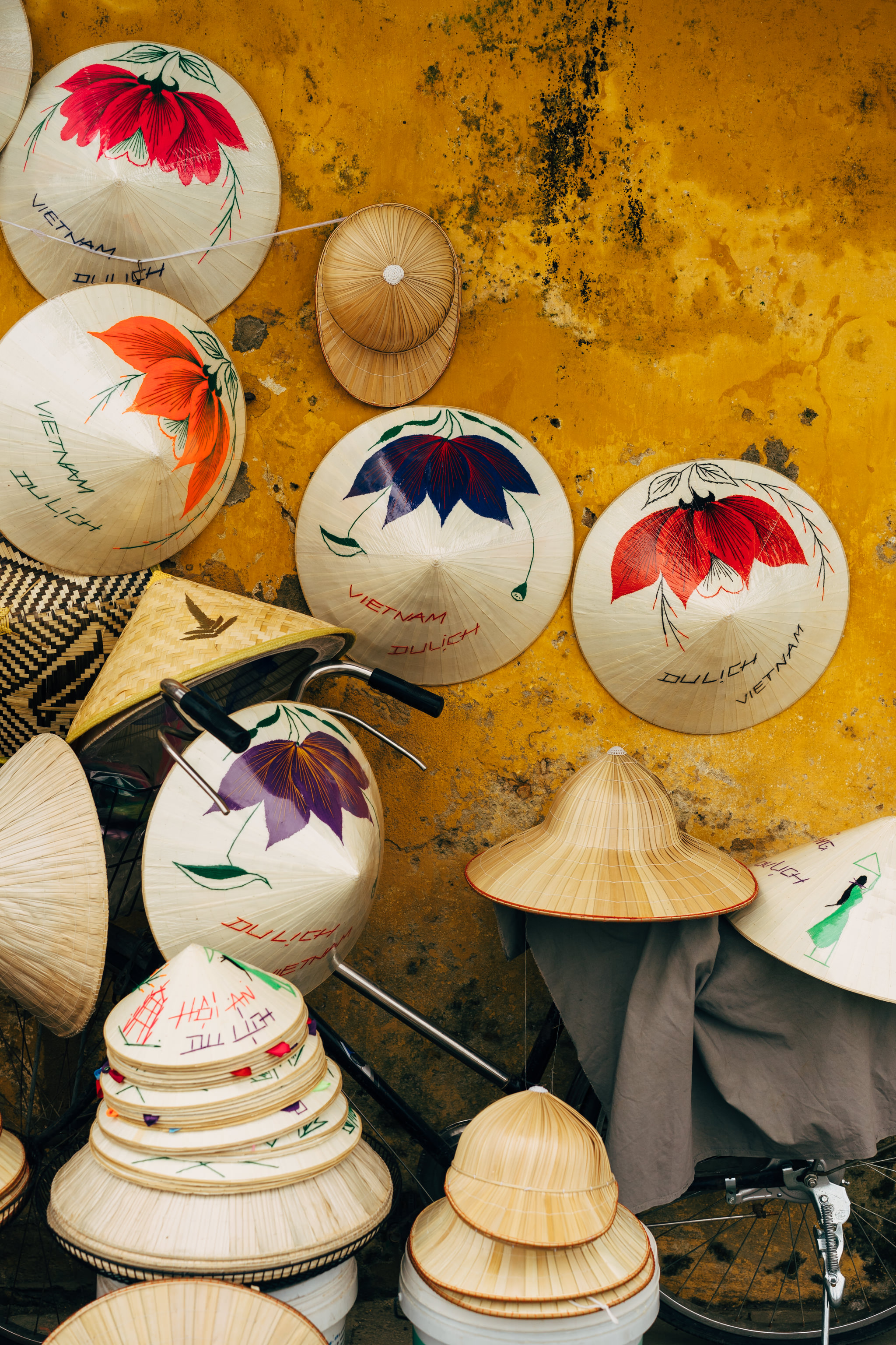 Vietnamese conical hats displayed against a yellow wall.