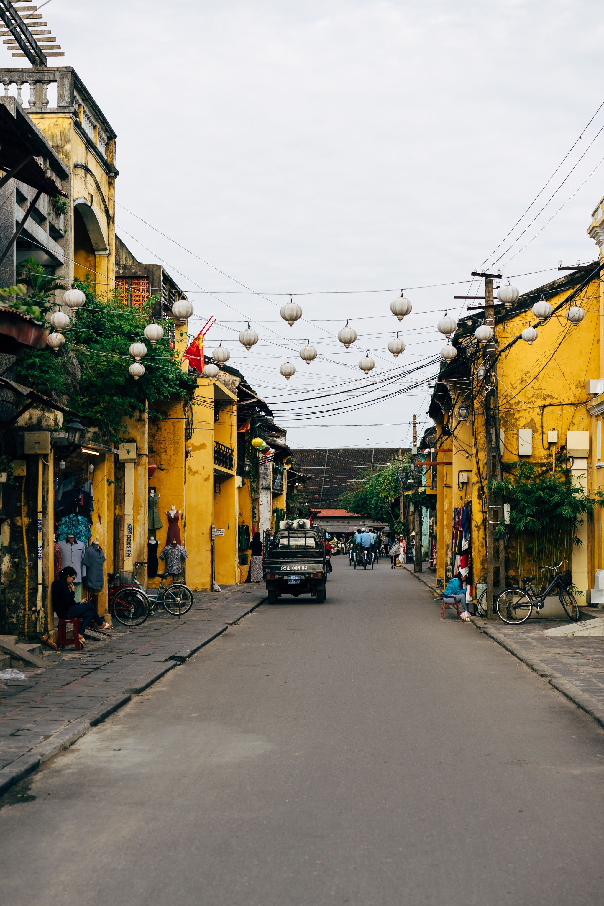 Hoi An, Vietnam street scene with yellow buildings, hanging lanterns, and people.