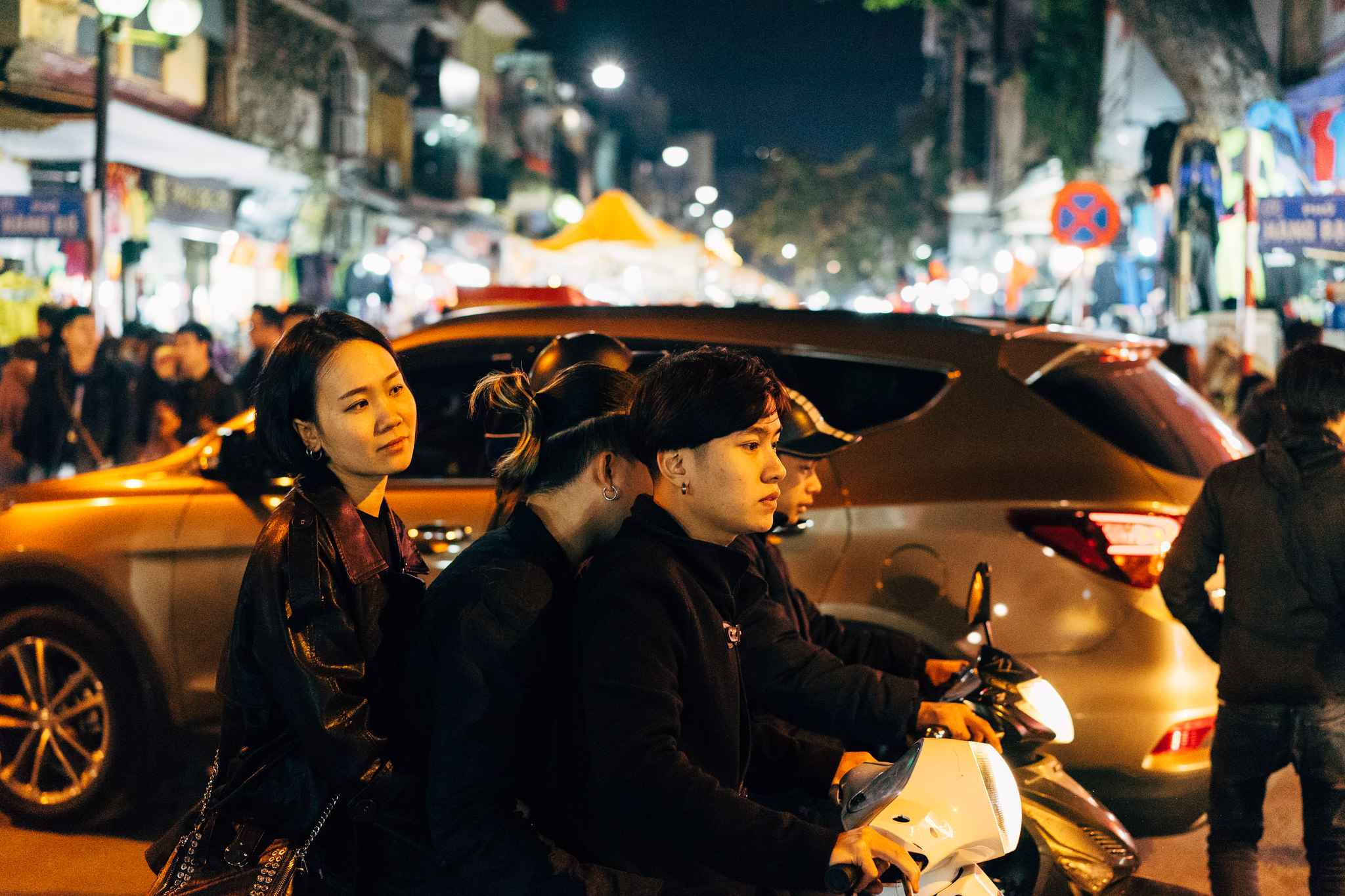 Two young women and two young men on a motorbike at night in Hanoi, Vietnam.