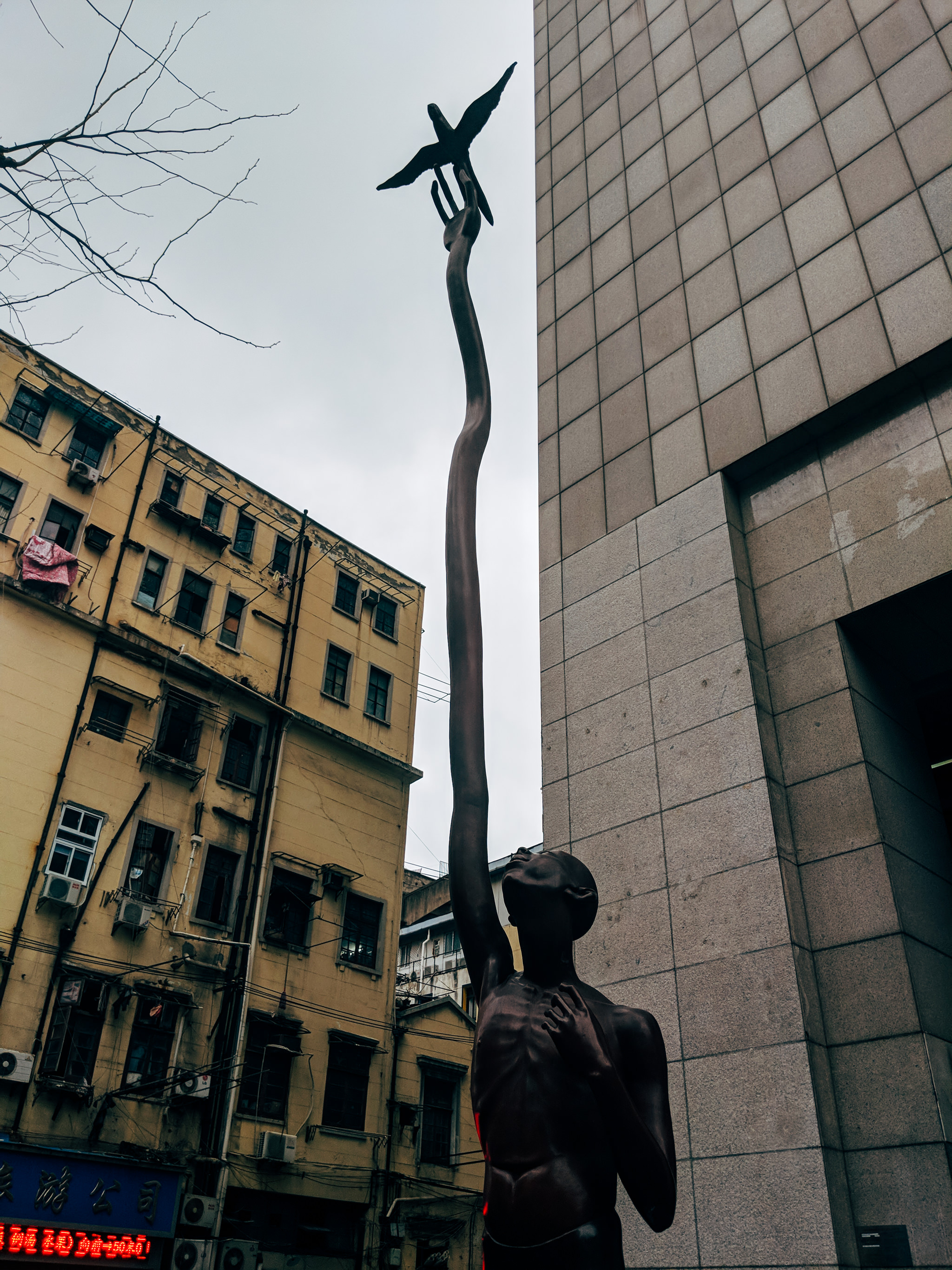 Bronze statue of a man reaching up to release a bird.