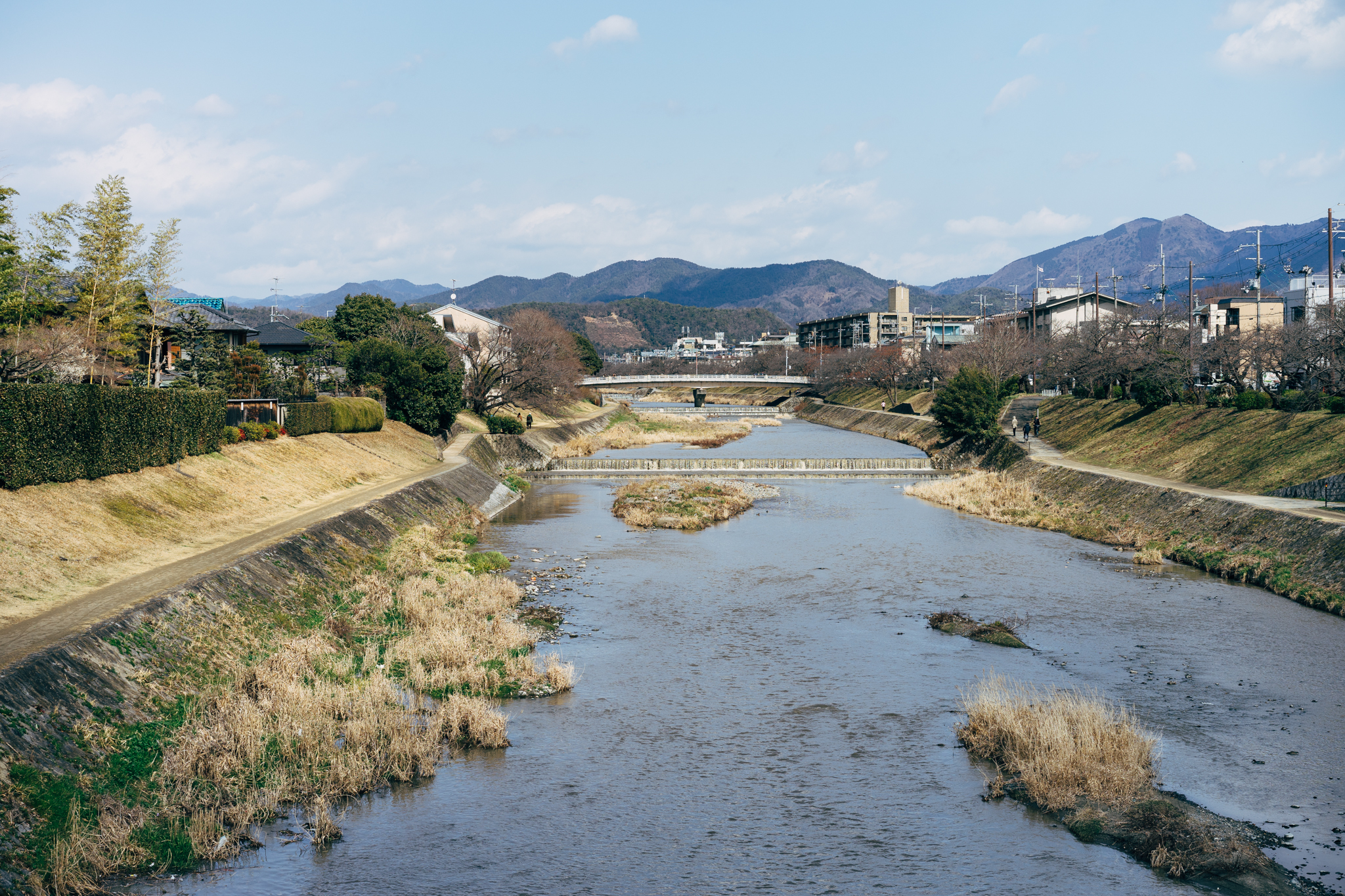 Takano River in Kyoto, Japan, with a bridge, houses, and mountains in the background.