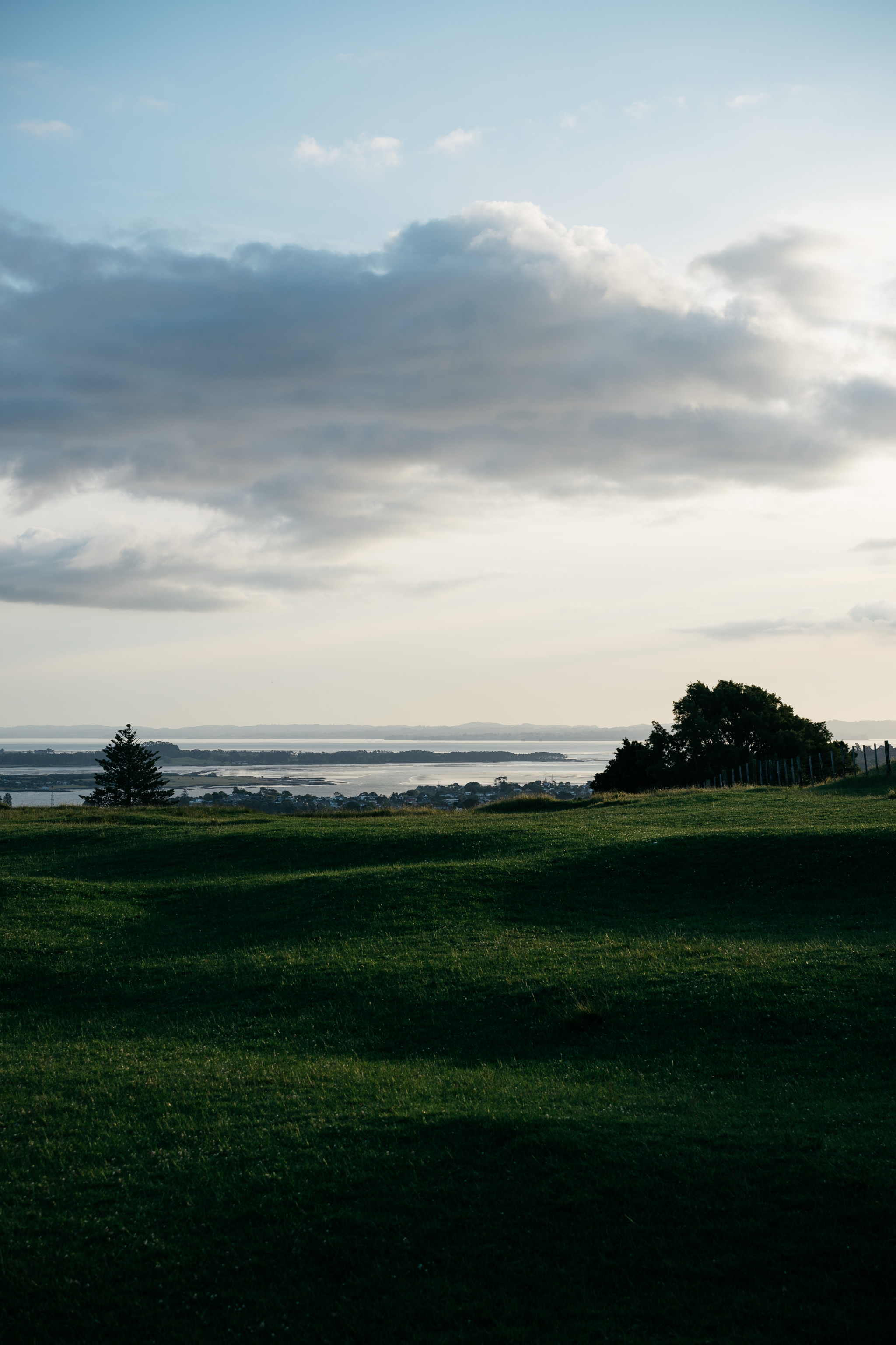 Auckland sunset over water and green field.