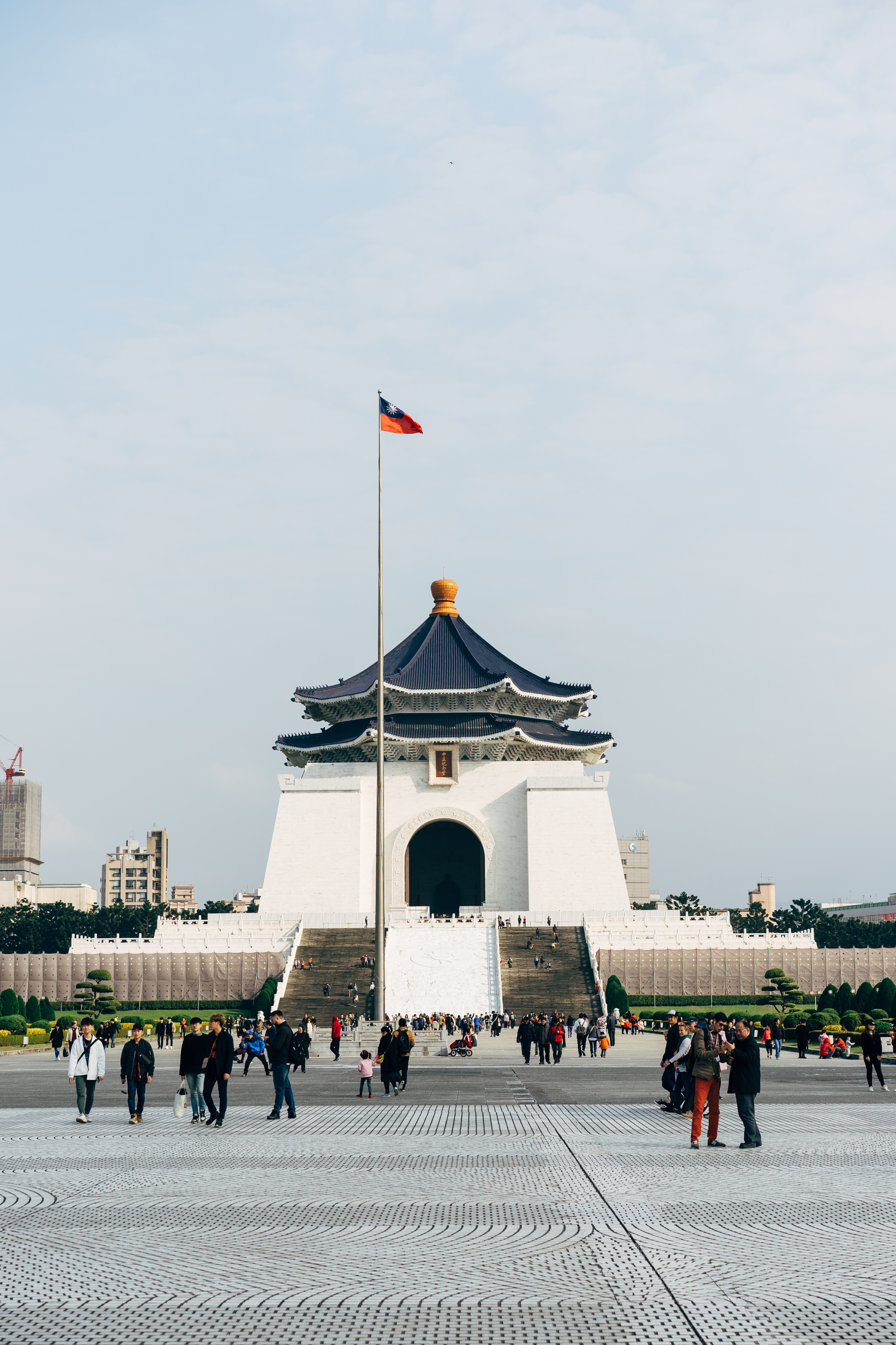 Chiang Kai-shek Memorial Hall in Taipei, Taiwan, with a flagpole and Taiwanese flag in the foreground.