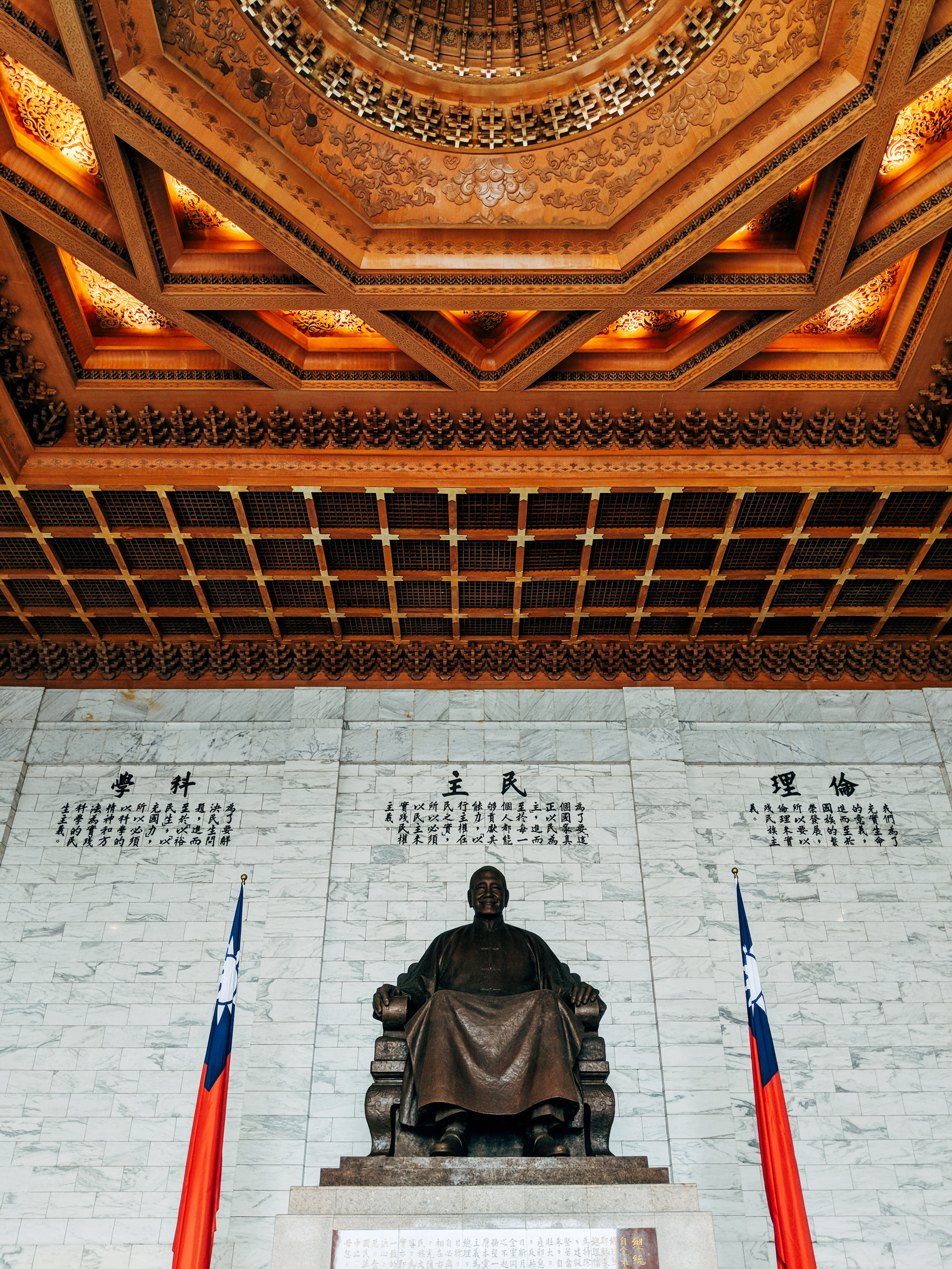 Bronze statue of Chiang Kai-shek in Chiang Kai-shek Memorial Hall, flanked by Taiwanese flags.