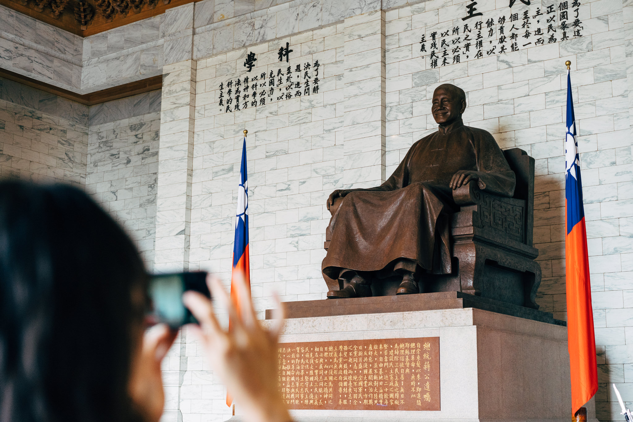 Bronze statue of Chiang Kai-shek, seated, with flags of Taiwan flanking it.