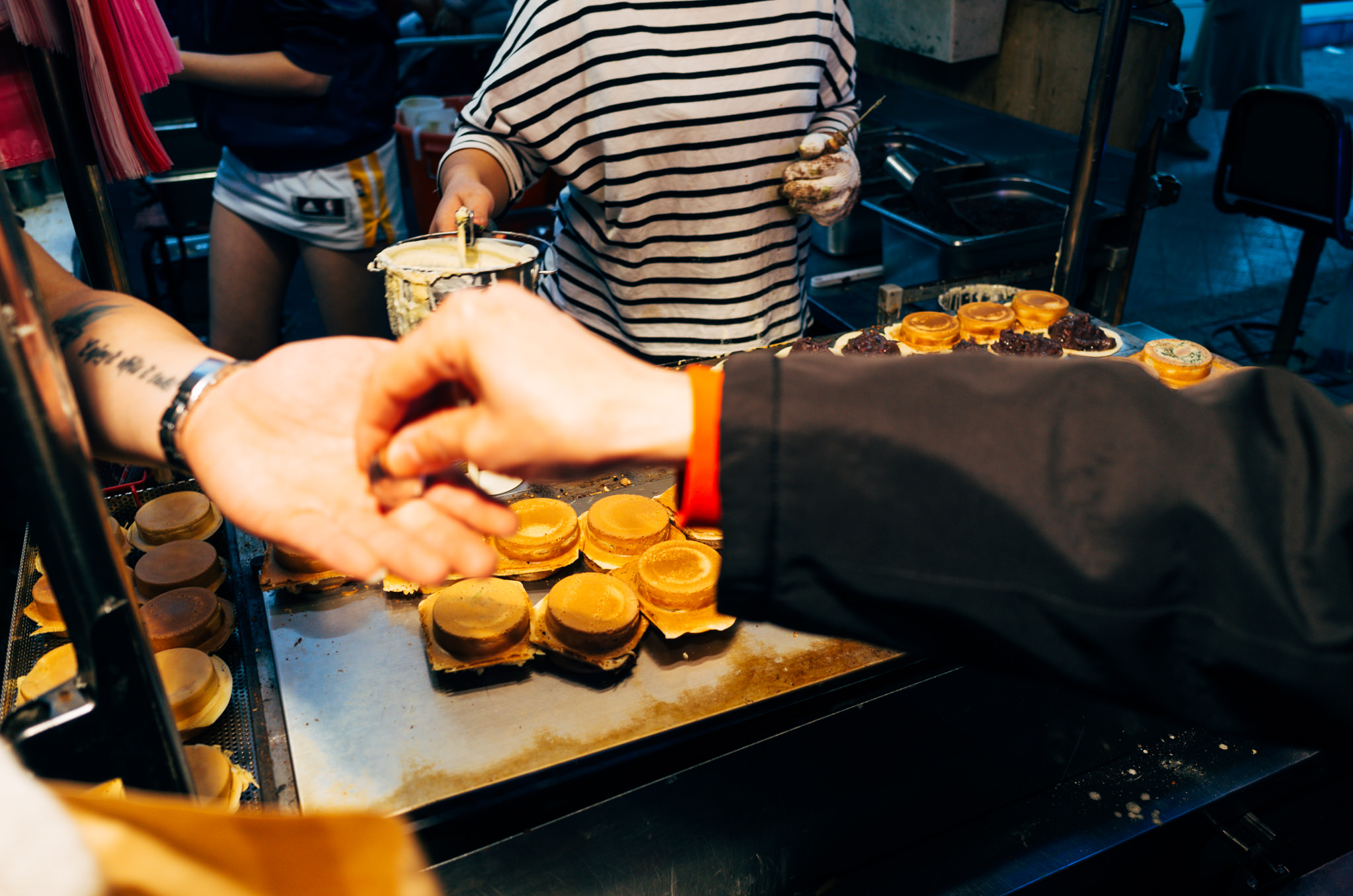 Close-up of hands receiving Taiwanese street food, likely a type of pancake, from a vendor.