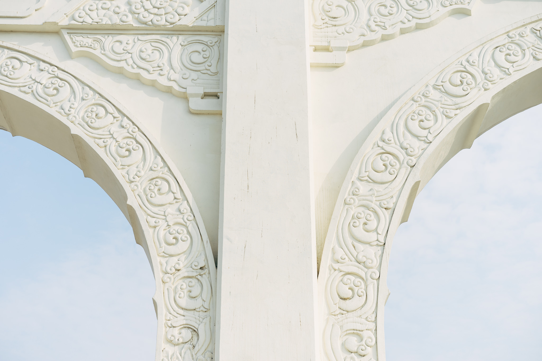 Close-up of ornate white stone archway with intricate carvings.