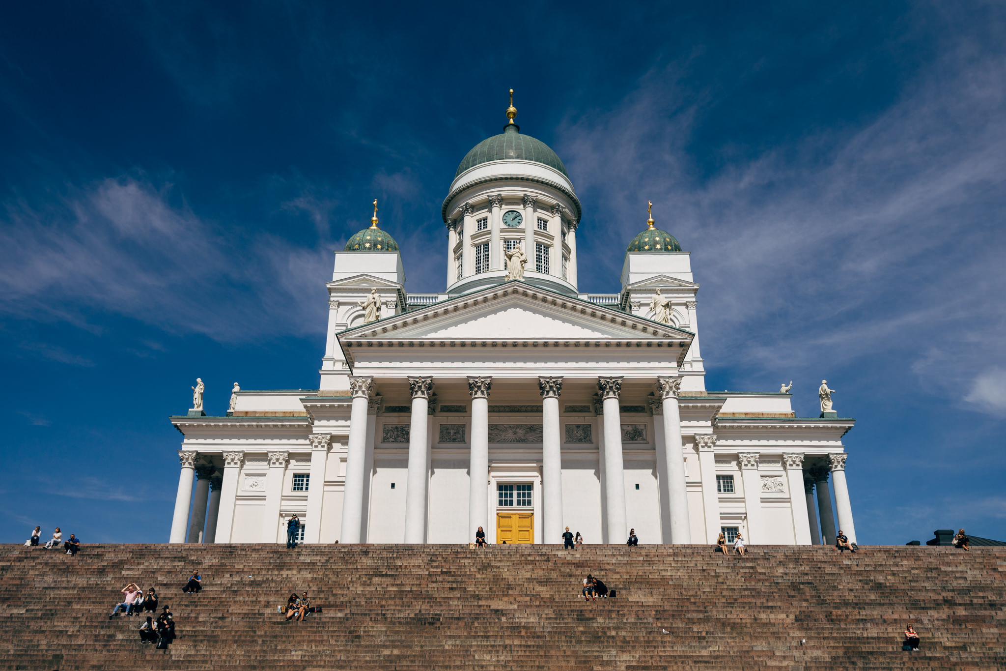 Helsinki Cathedral with people sitting on the wide steps in front.